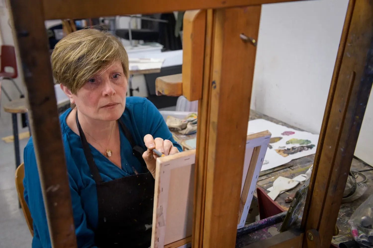student masterscholing 2 werkt aan schilderij op een ezel in een vaklokaal