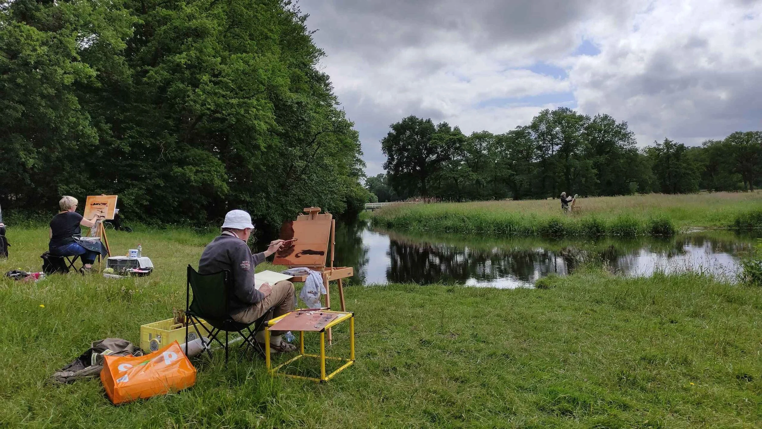 cursisten zitten achter ezels bij het water en zijn aan het werk tijdens de workshop buitenschilderen van joost doornik