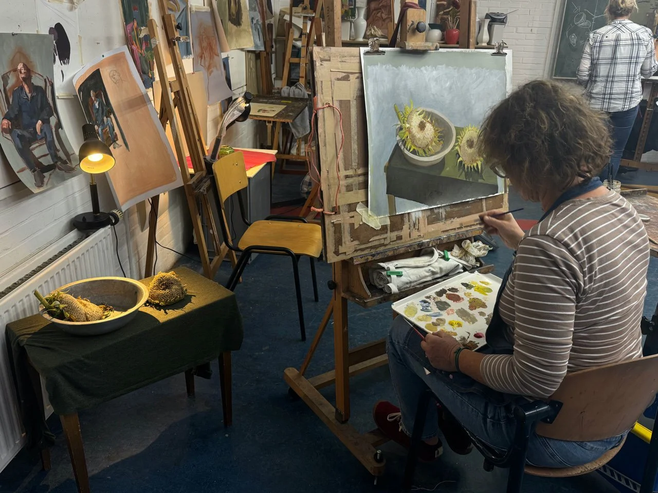 een student schildert zonnebloemen na in een atelier