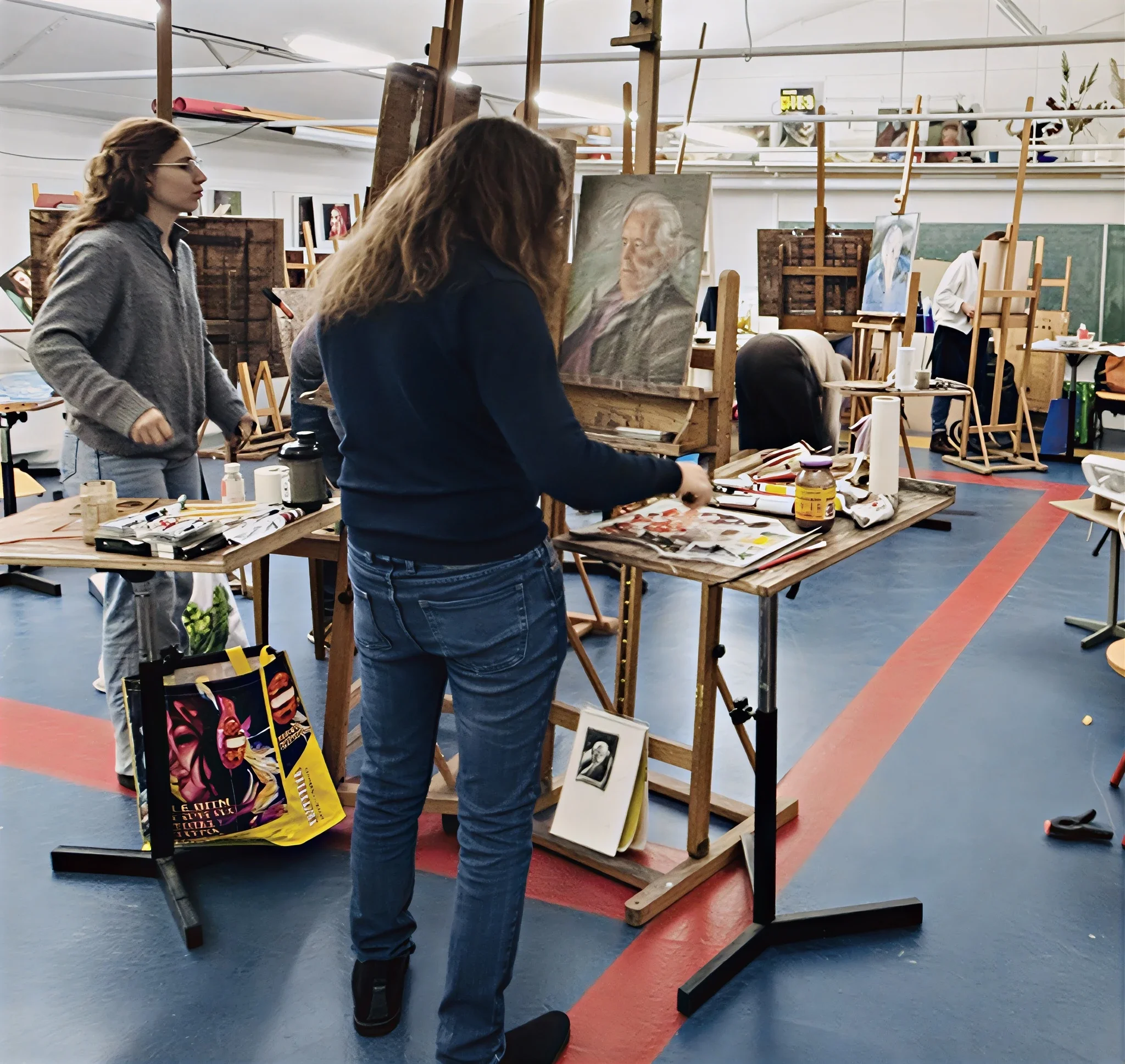 twee studenten werken aan een portret op twee ezels