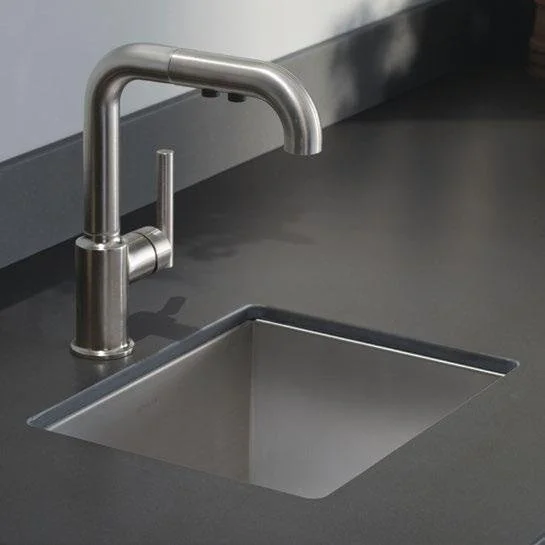 Close-up of a stainless steel kitchen sink with a modern faucet on a dark countertop.