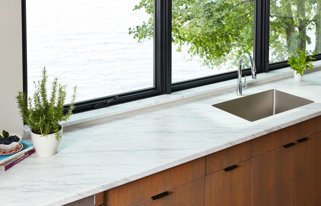 Kitchen countertop with a stainless steel sink and a view of a body of water outside the window.