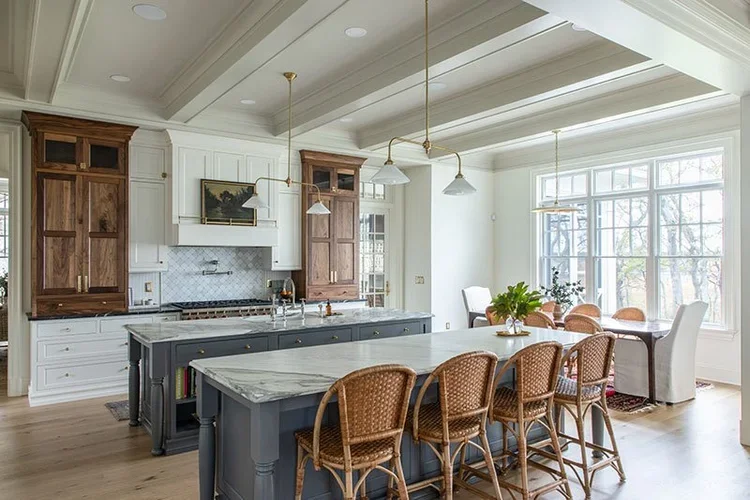 Bright, spacious kitchen and dining area with white walls, large windows, kitchen island, and wooden accents.