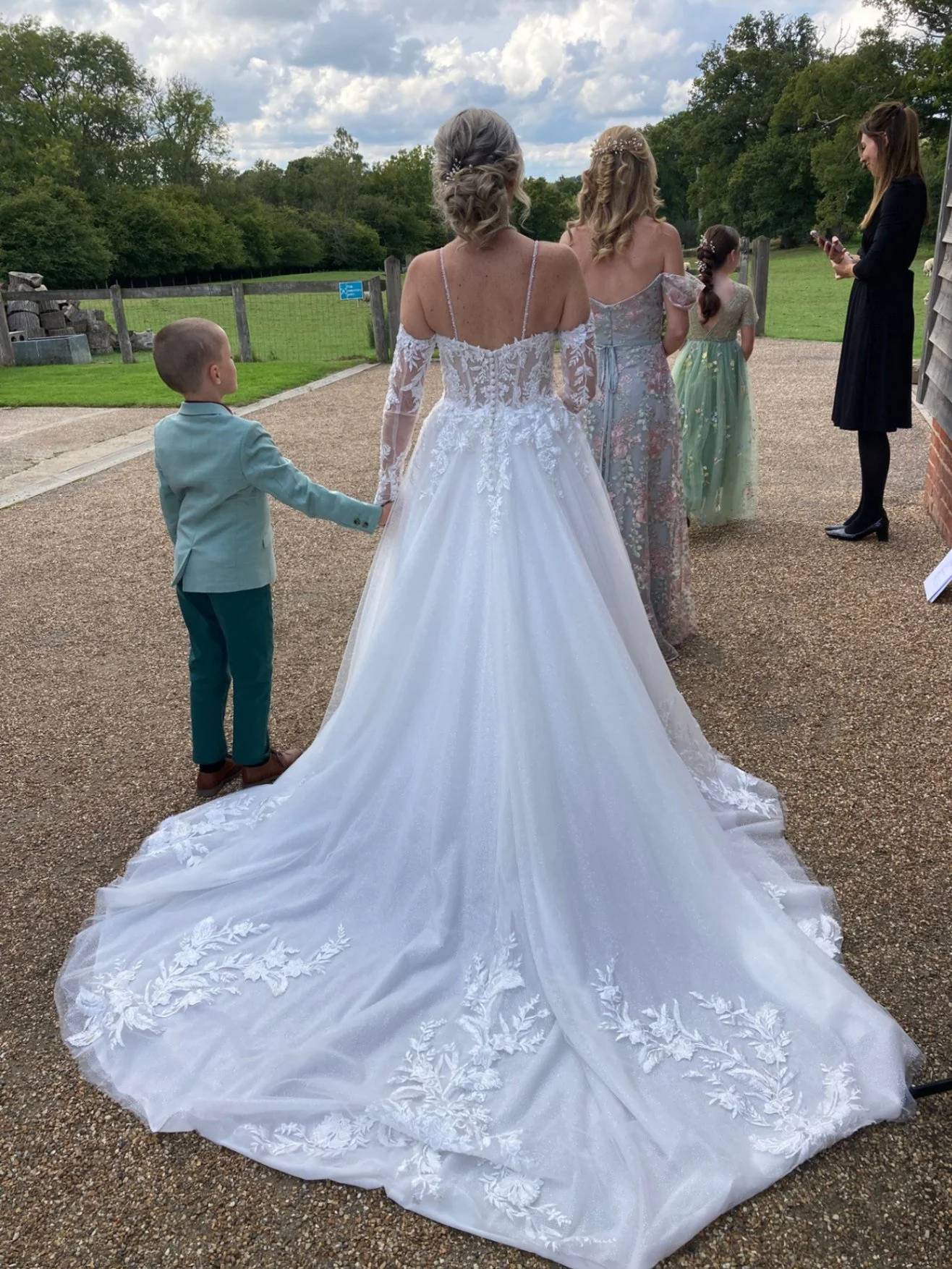 Bride in wedding dress walking outdoors with guests