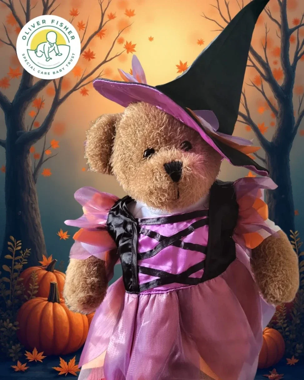 Teddy bear dressed in Halloween costume with witch hat and purple outfit set against seasonal illustrated background