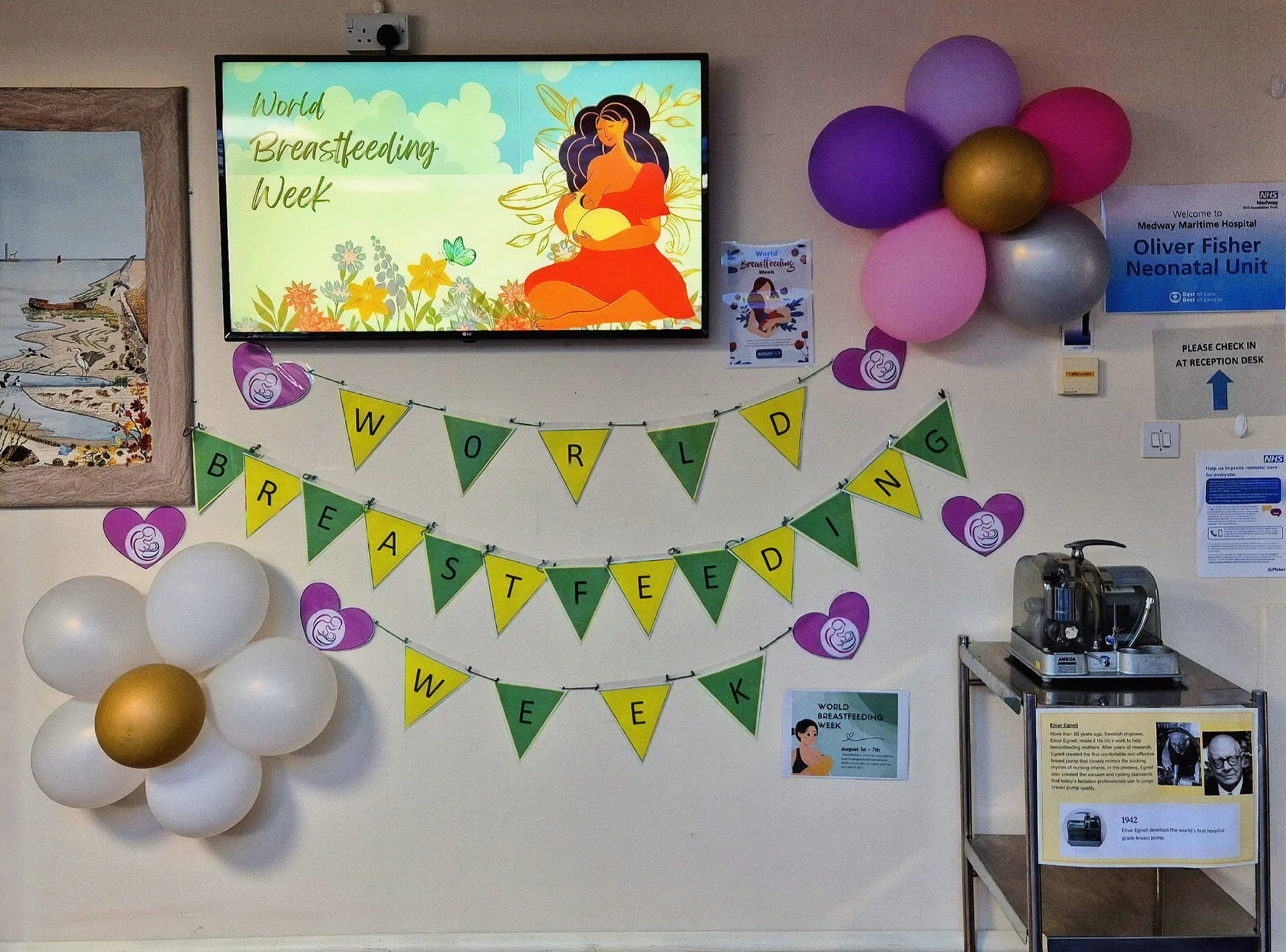 white purple and gold balloons around a yellow and green banner that reads world breastfeeding week