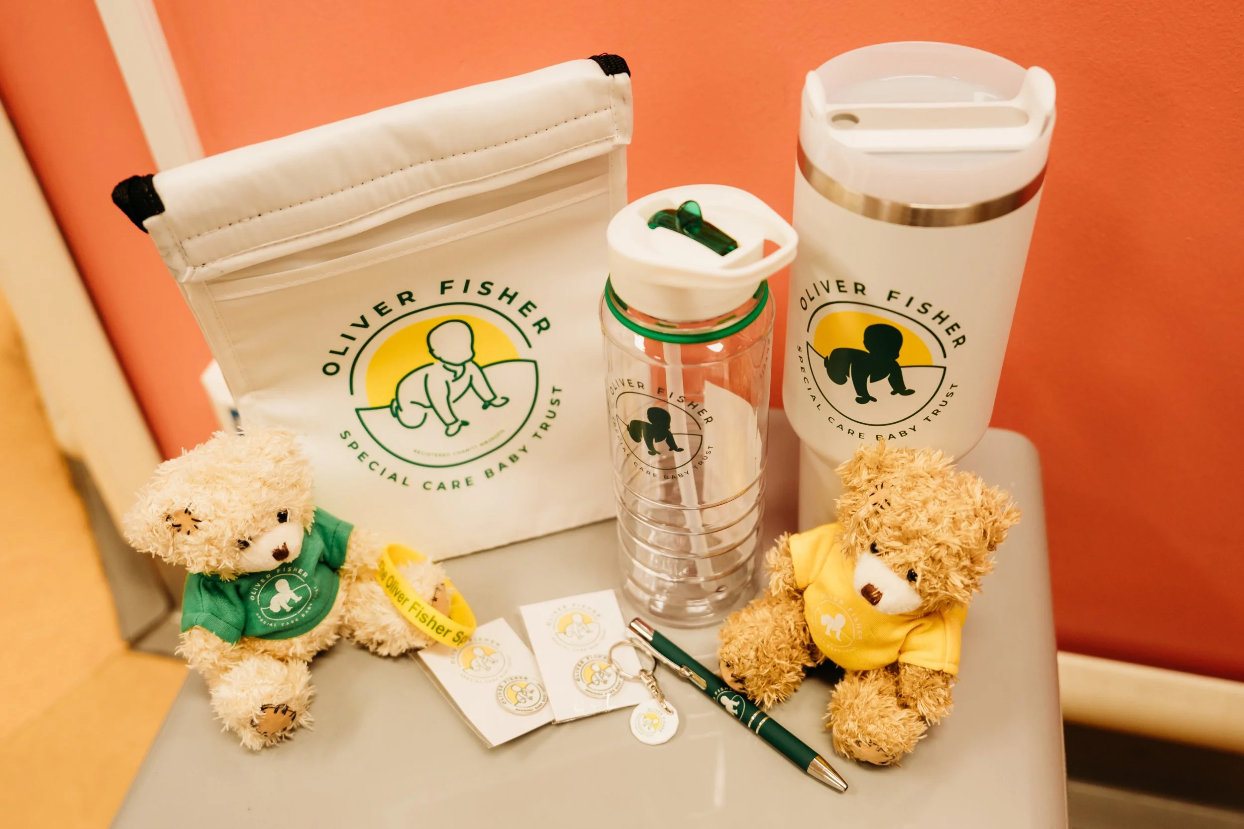 Selection of branded merchandise including reusable cup water bottle teddy bears and branded accessories arranged together