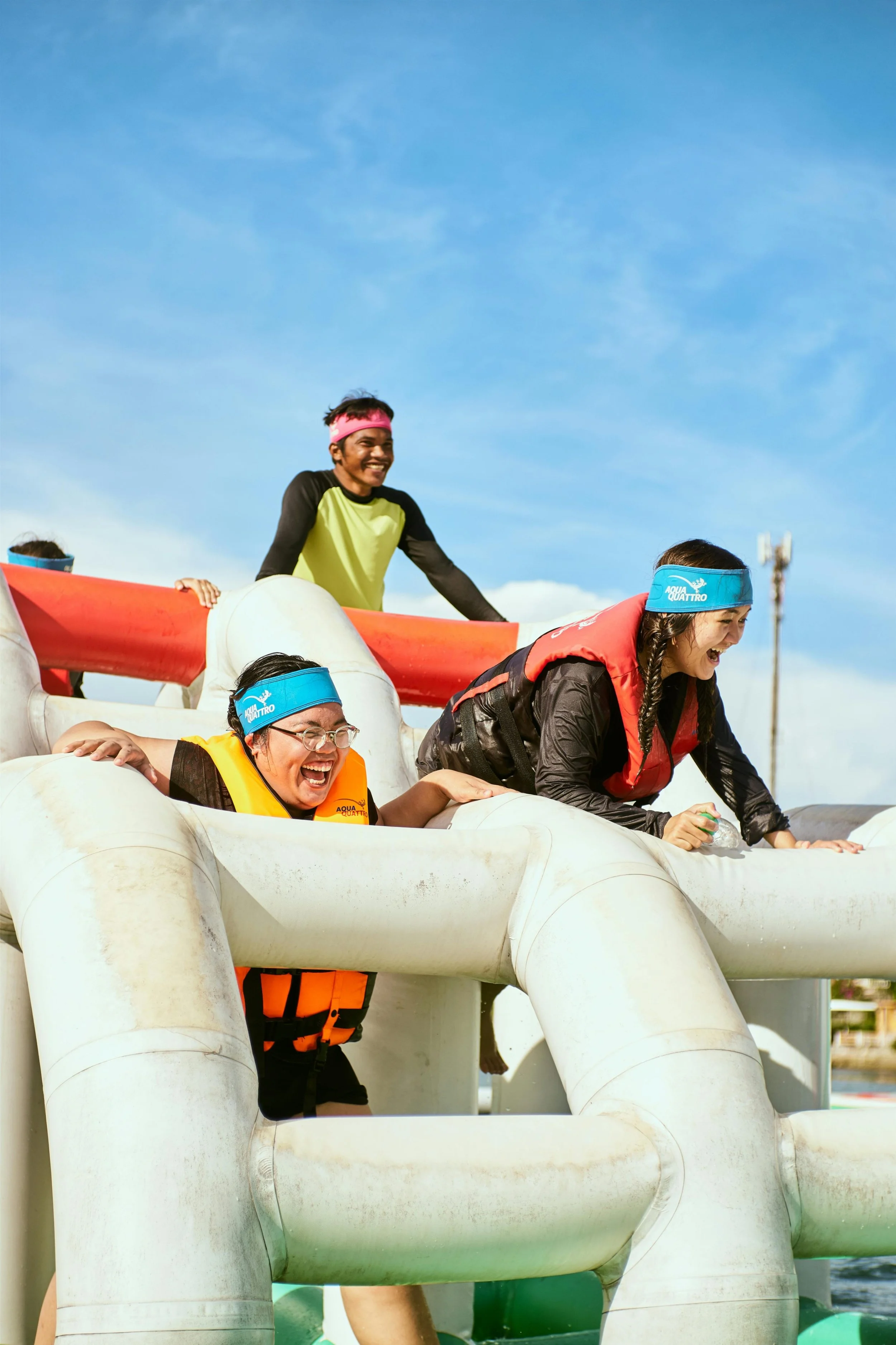 Adults taking part in inflatable obstacle course laughing and climbing over large structures during charity event