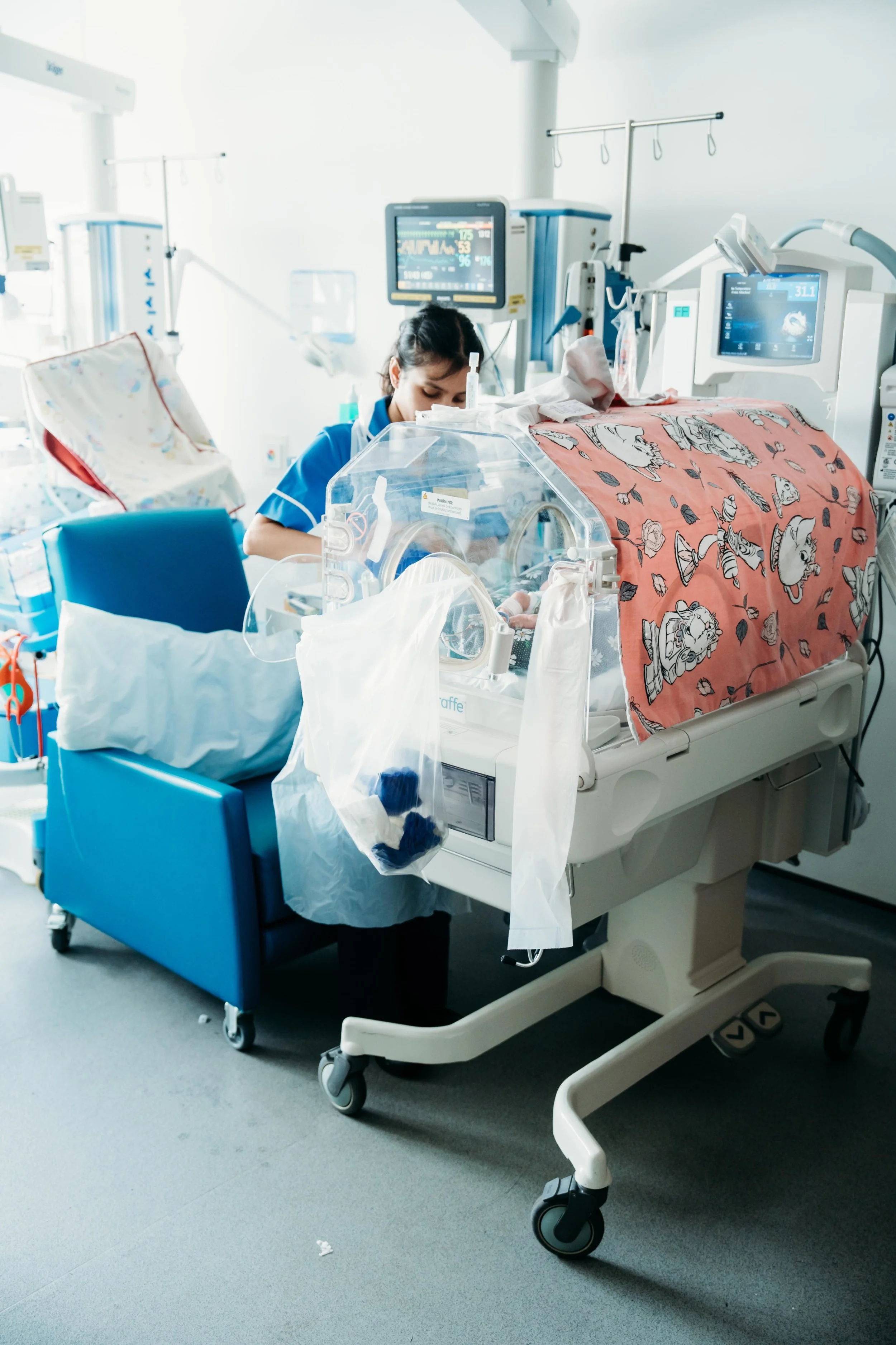 Baby receiving specialist neonatal care in hospital unit surrounded by monitoring equipment