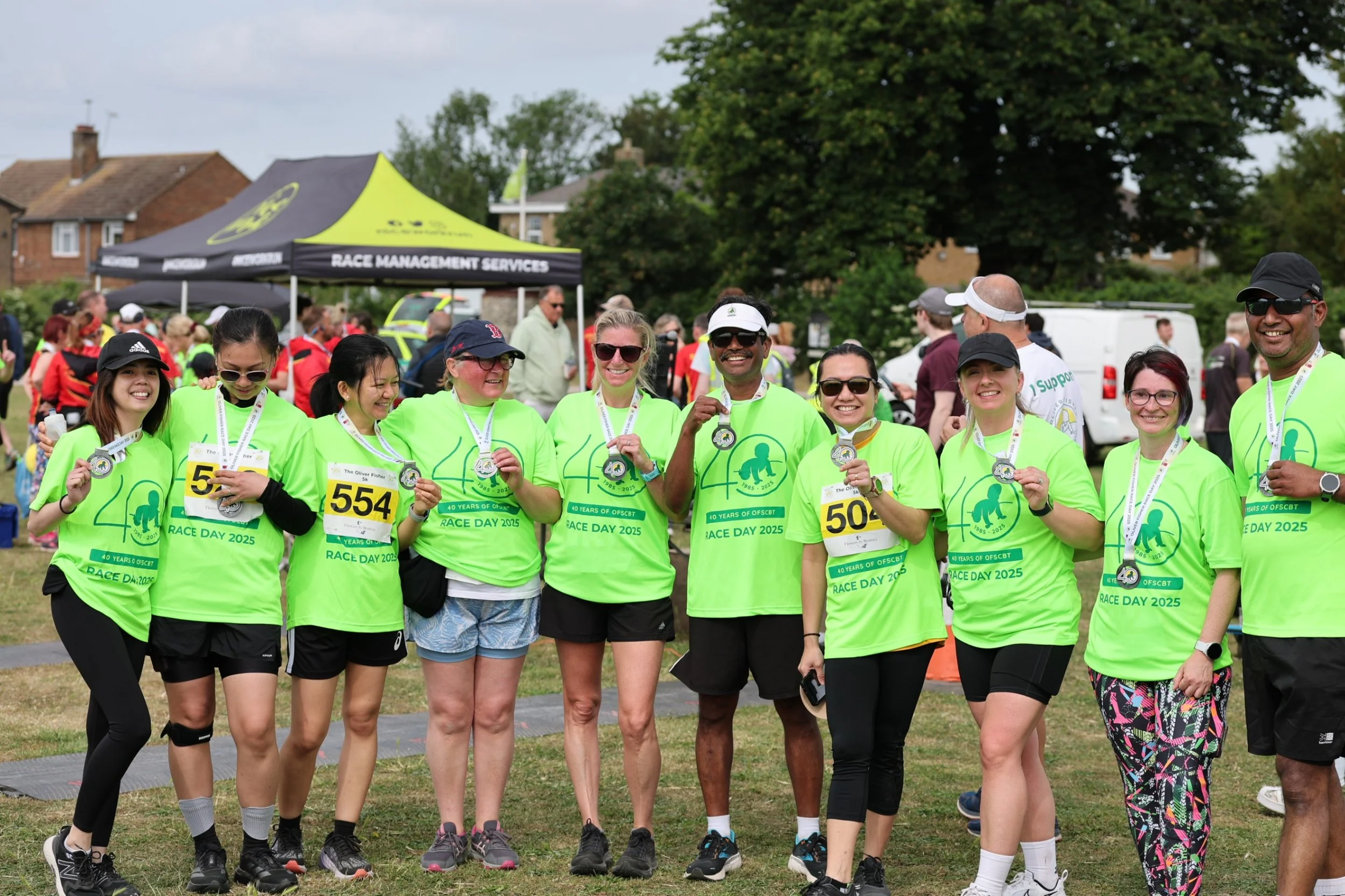 Group of runners in charity t shirts holding medals smiling