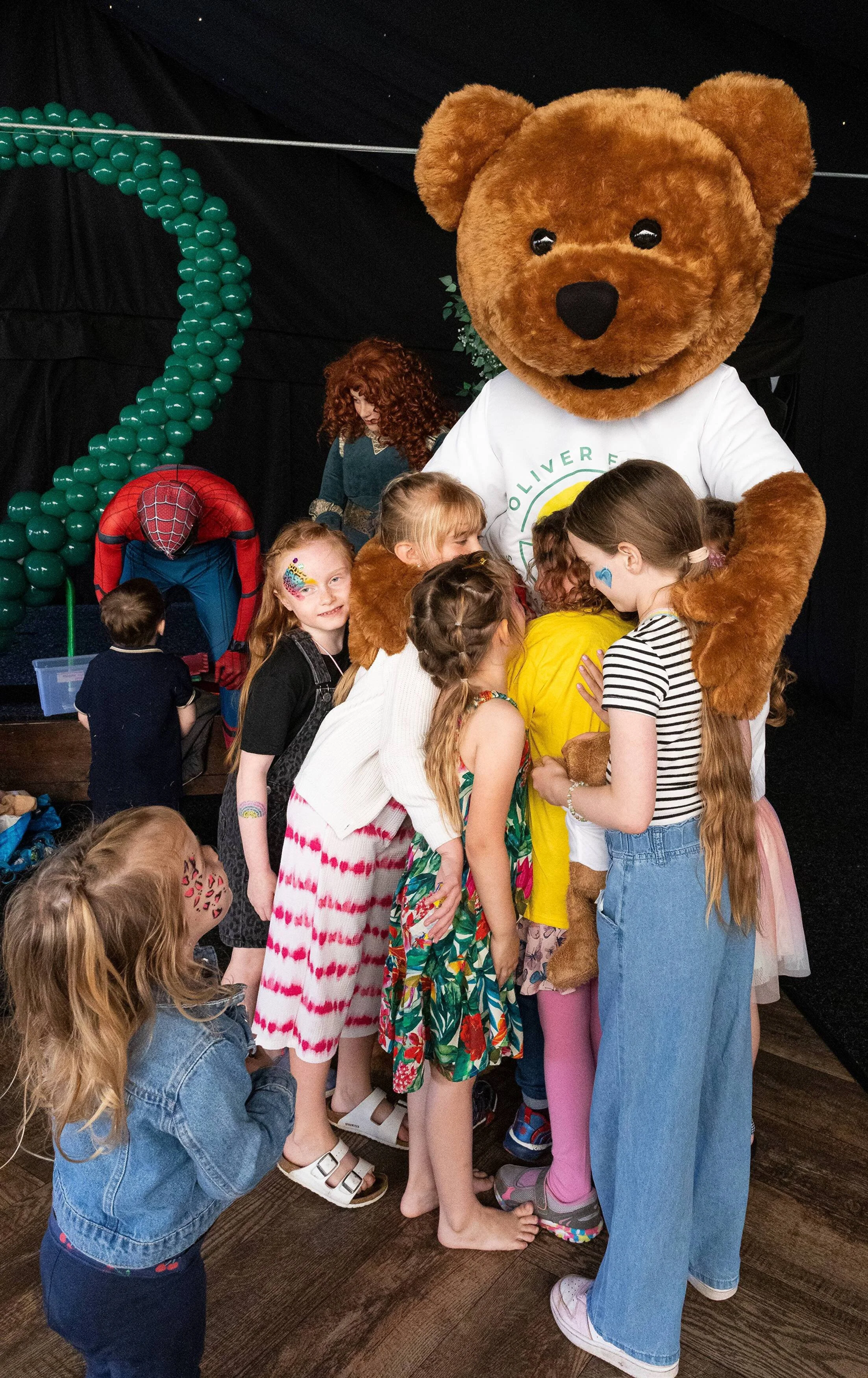 Photo of Oliver Fisher Trust mascot bear being hugged by children