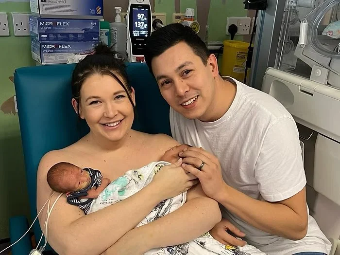 Mother and father holding premature baby during skin to skin care in NICU