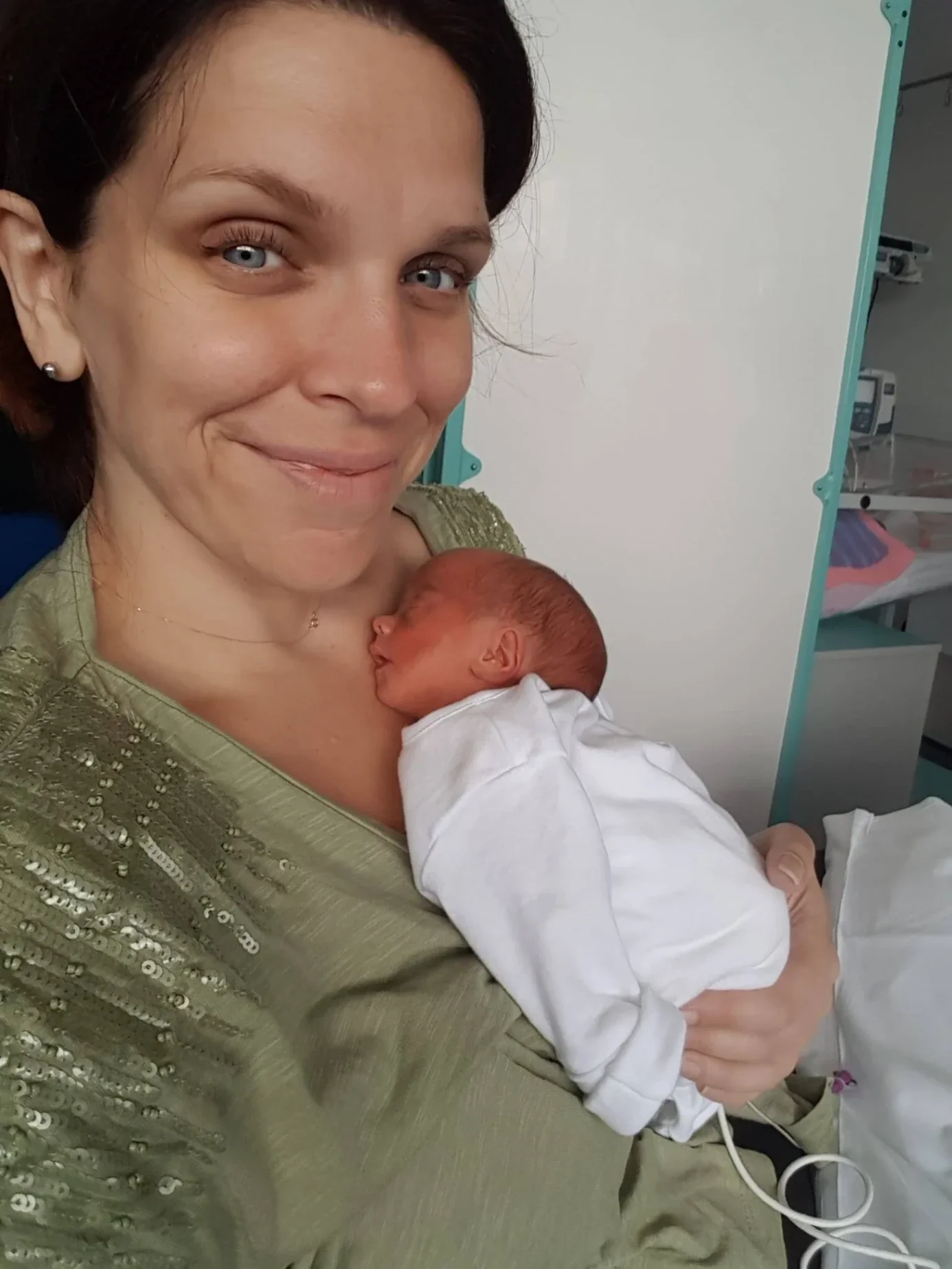 Parent holding a premature baby close to their chest in a neonatal unit setting