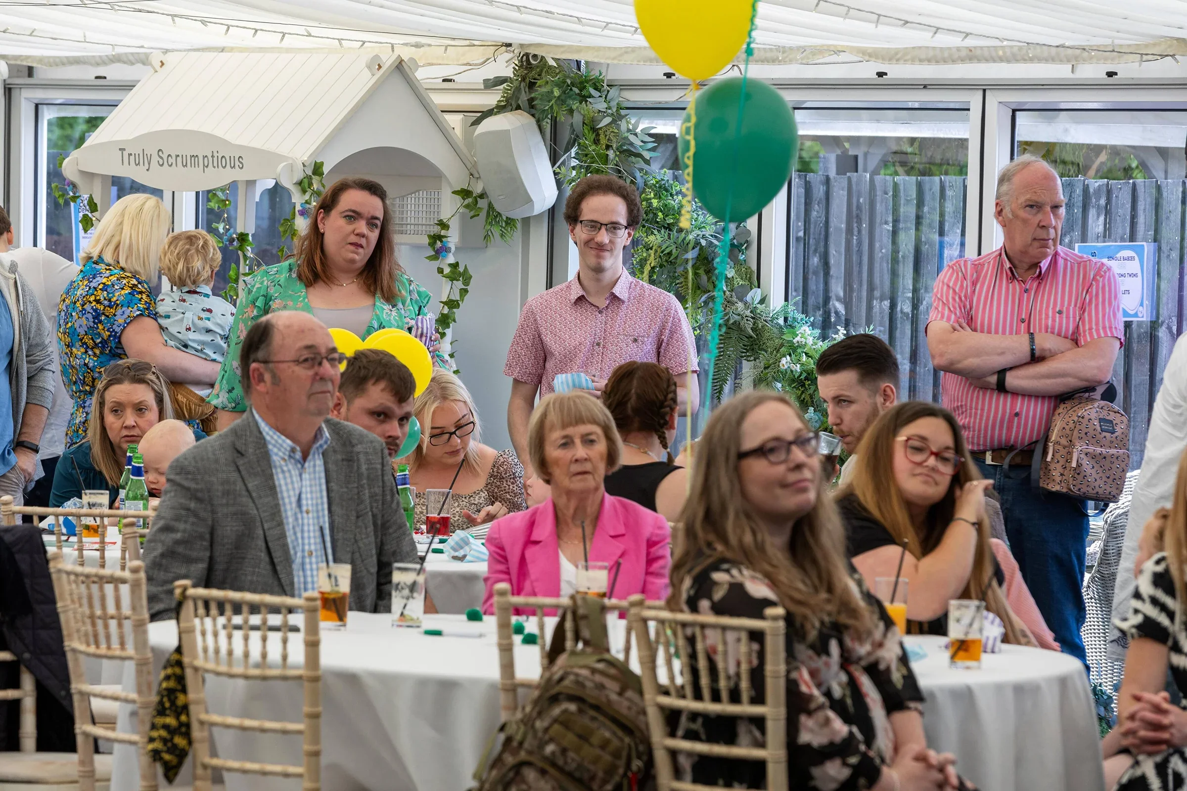 Photo of people sitting around tables at an event, listening to a speech