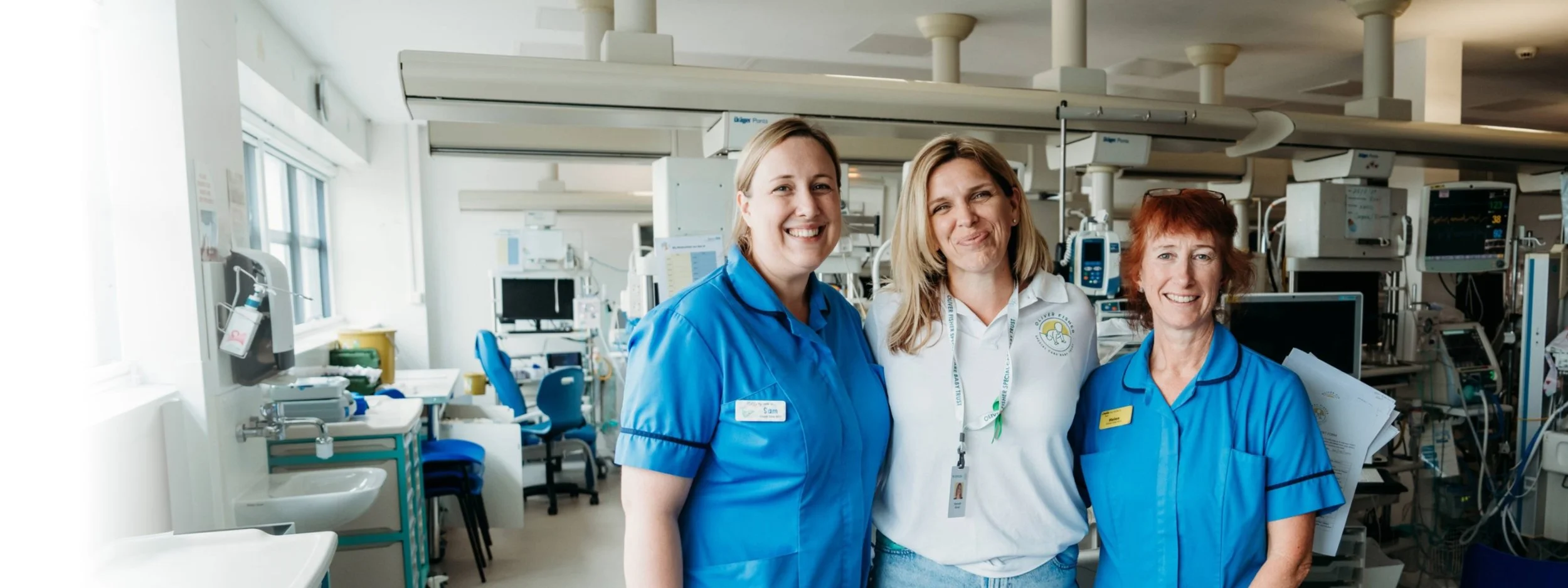 Three team members smiling together inside the Oliver Fisher Neonatal Unit