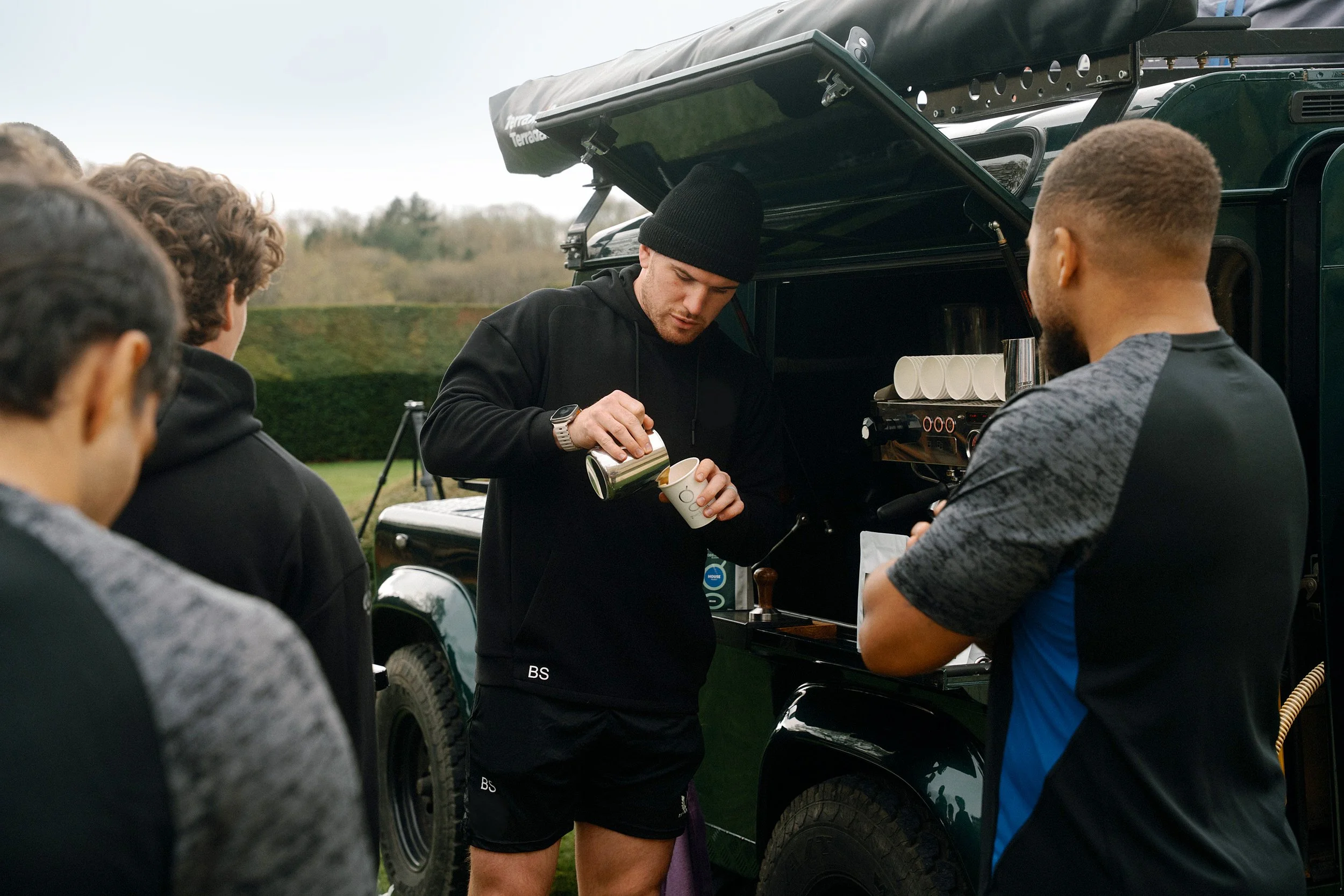 Bath Rugby Captain Ben Spencer pours a grass & roots coffee next to his landrover