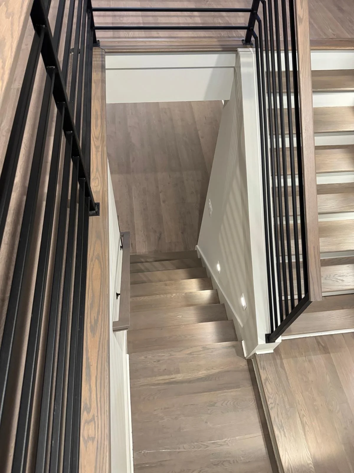 Top view of a staircase with wooden steps, black metal railing, and a private landing area.