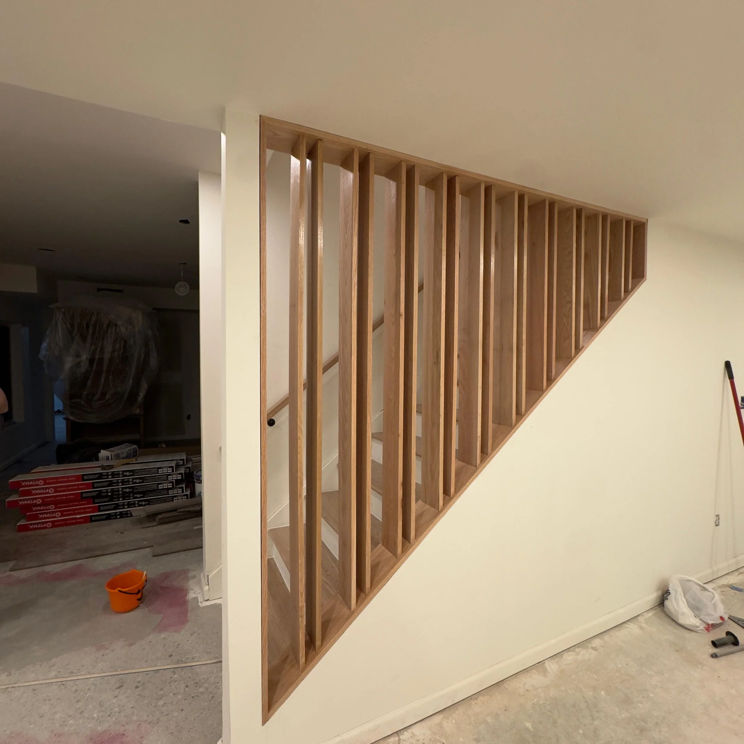 Unfinished wooden partition wall in a room under construction, with construction materials and tools on the floor.