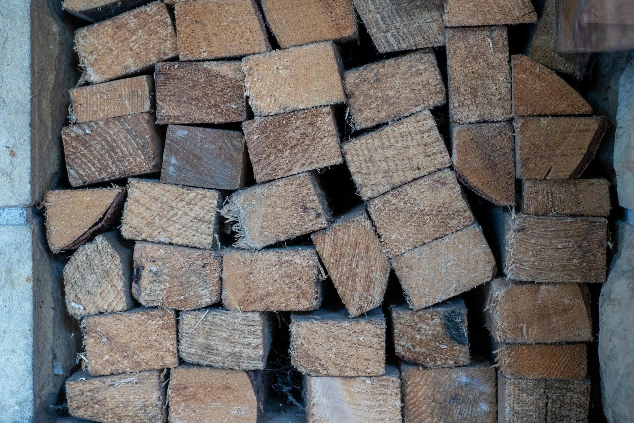 Stack of cut firewood logs arranged in a rectangular frame, ready for burning or storing.