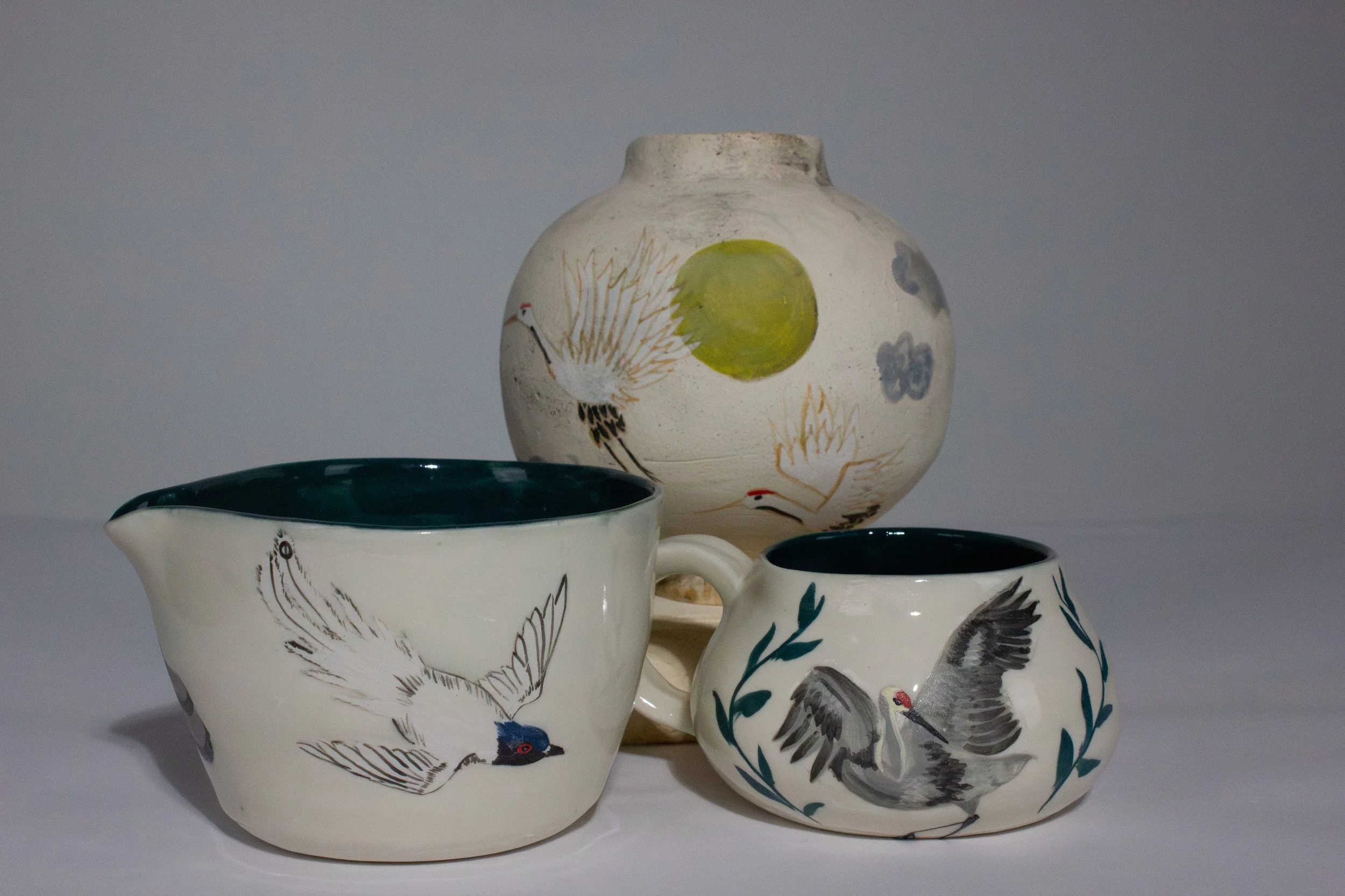 "Flycatcher Bowl" (Left), "Twin Cranes Jar" (Middle), "Dancing Crane Mug" (Right). 2026