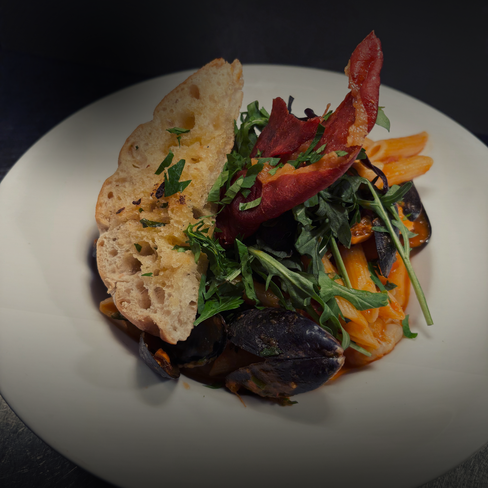 Seafood Penne Pasta in a Tomato and Chorizo Sauce with Parma Ham Crisp and Garlic Foccacia