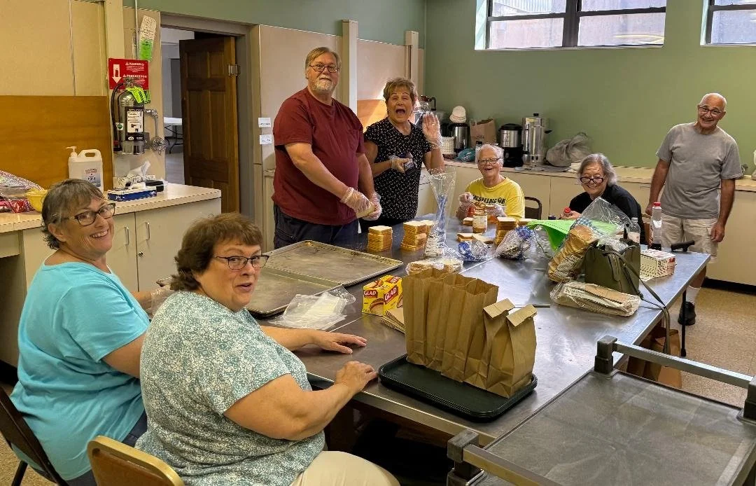Group of people assembling food packages in a kitchen or community center