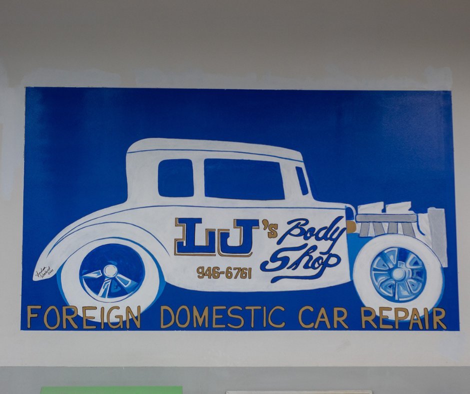 Sign for JJ's Body Shop, a car repair shop. The sign features a white vintage car illustration with blue and gold text. It states 'JJ's Body Shop' with a phone number 946-6761, and the text 'Foreign Domestic Car Repair' at the bottom.