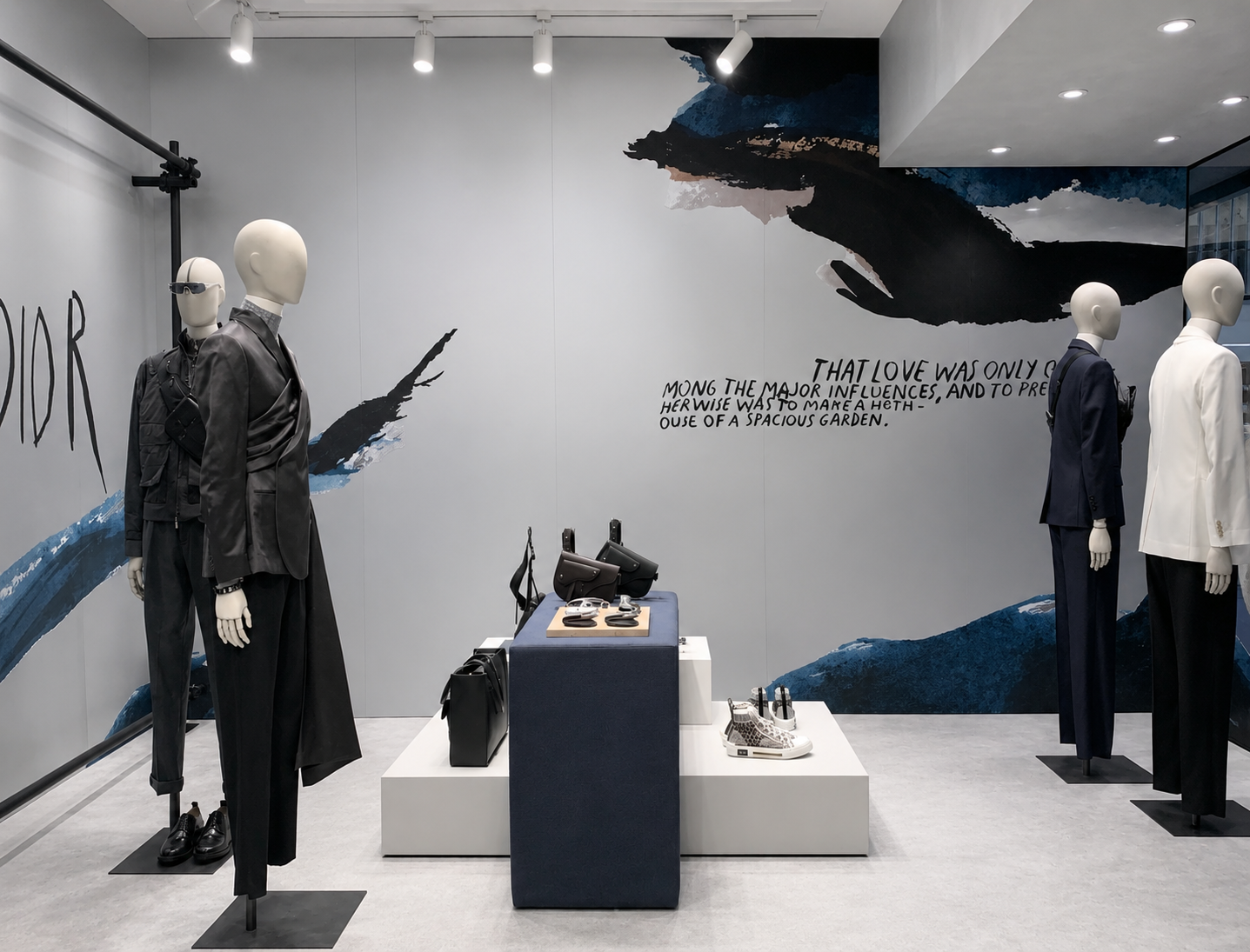 Vitrine de mode avec mannequins portant des costumes, sacs à main et chaussures dans un espace de magasin avec une décoration murale artistique et un texte en anglais.