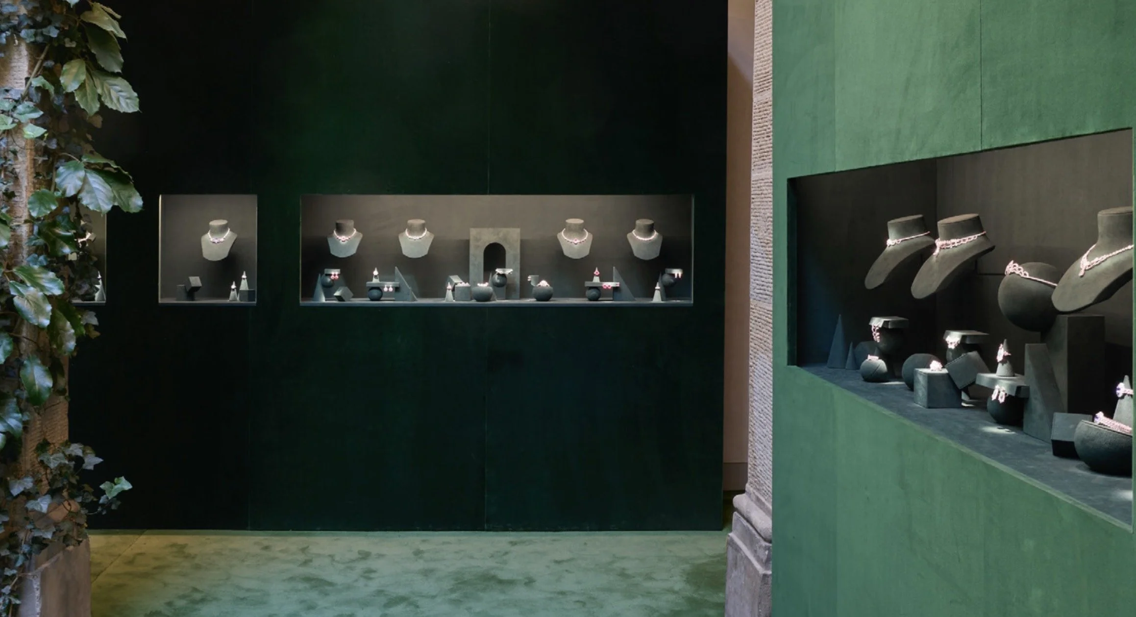 Vitrine de bijoux avec colliers et pendentifs exposés sur des supports noirs dans une boutique.