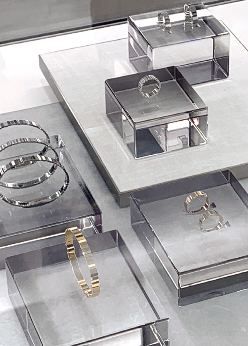 Bague en or et en argent exposée sur une surface en verre dans une vitrine de magasin de bijoux.
