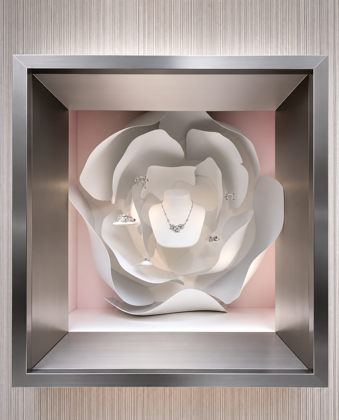 Vitrine avec des bijoux en argent, orné d'une décoration en papier blanc en forme de fleur sur fond rose et cadre en métal.