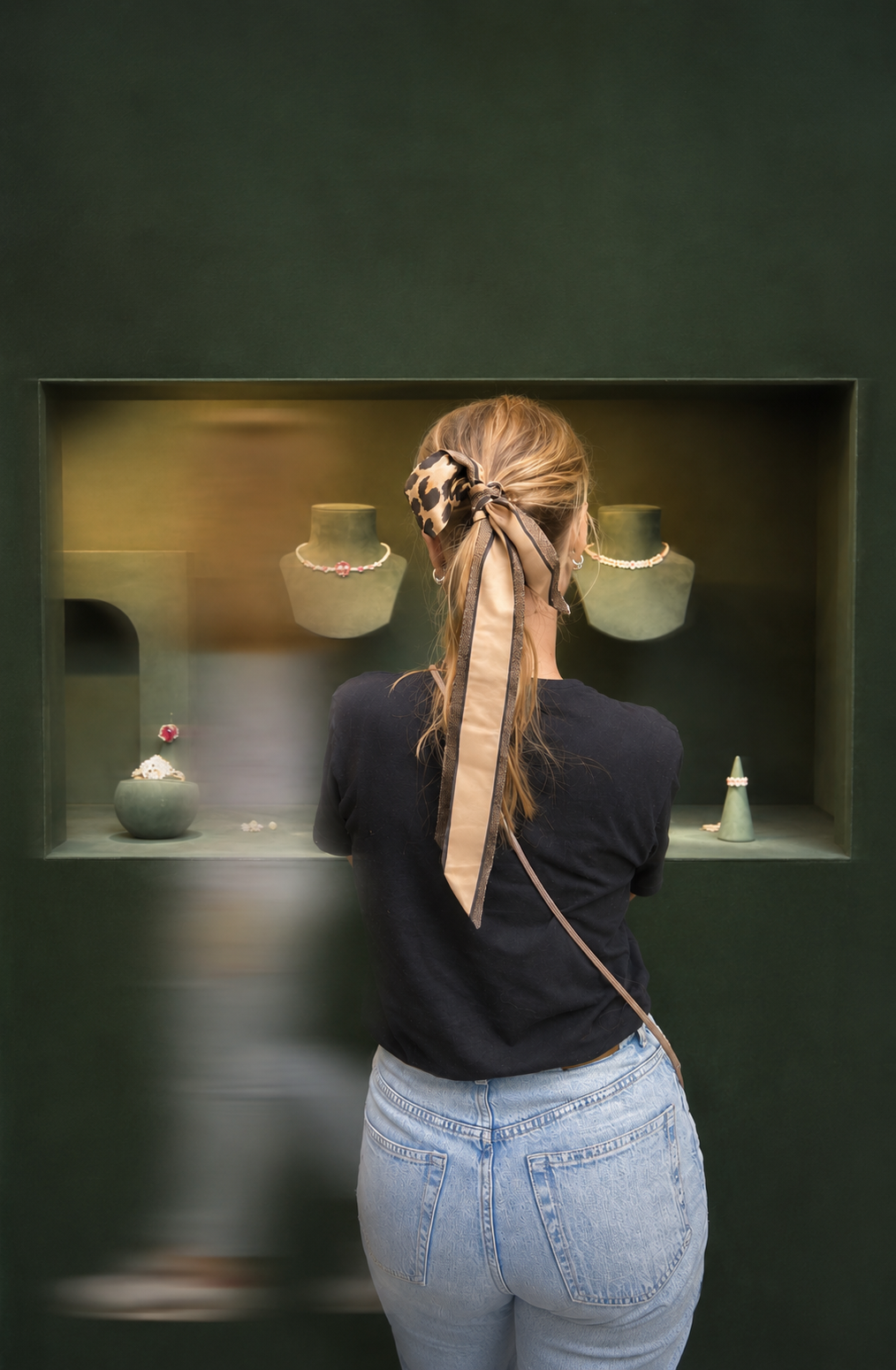 Une femme vue de dos regarde une vitrine de bijoux dans une boutique