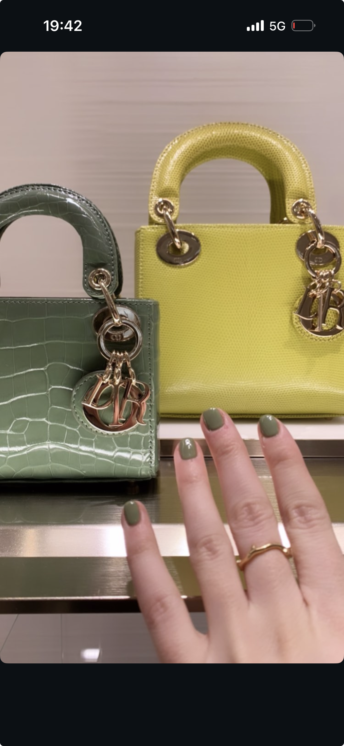 Deux petites sacs à main de couleur vert et jaune avec des poignées en forme de demi-cercle et des cadenas en métal, exposés sur un étagère en magasin.