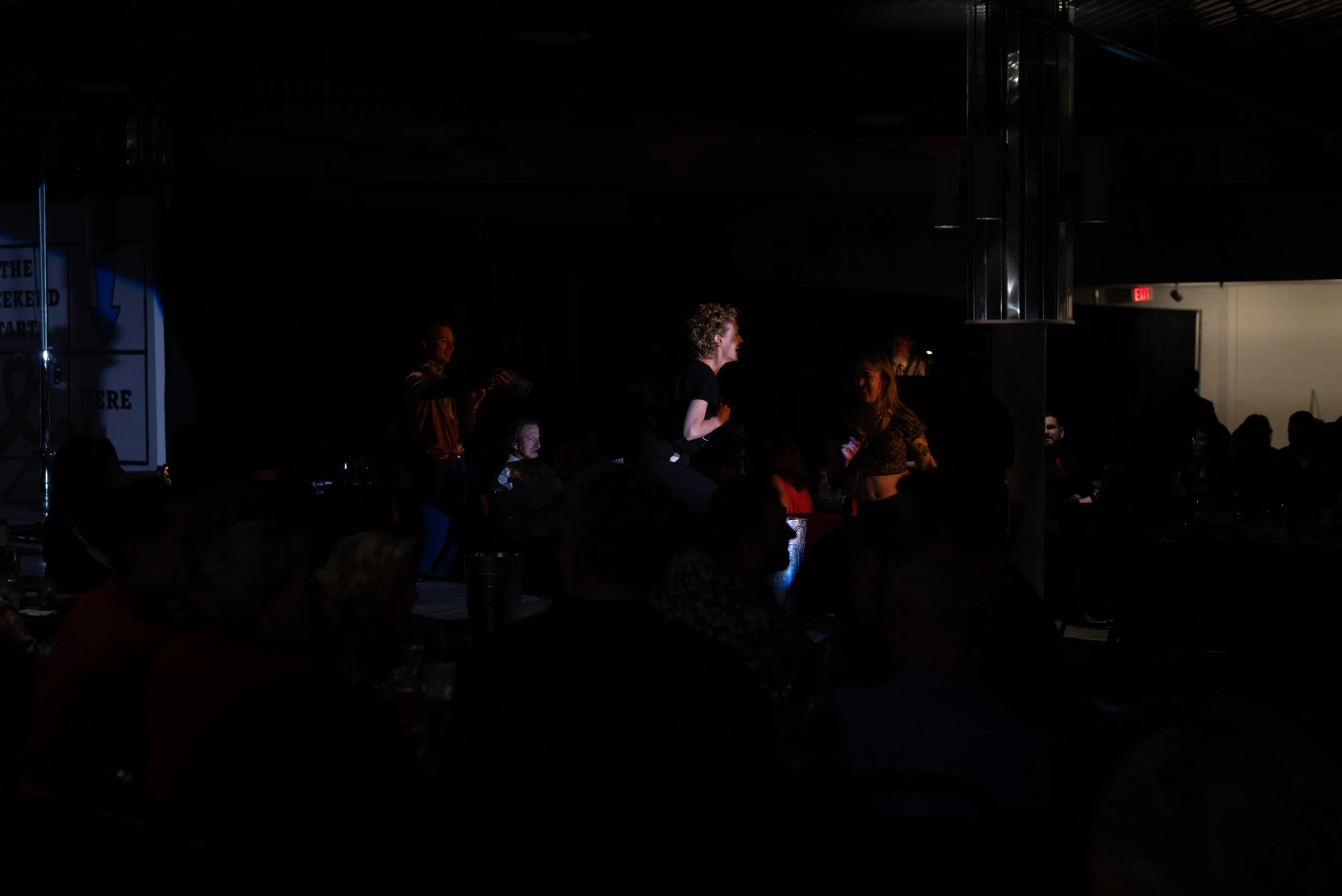 People dancing on stage at a live event with an audience in the dark.