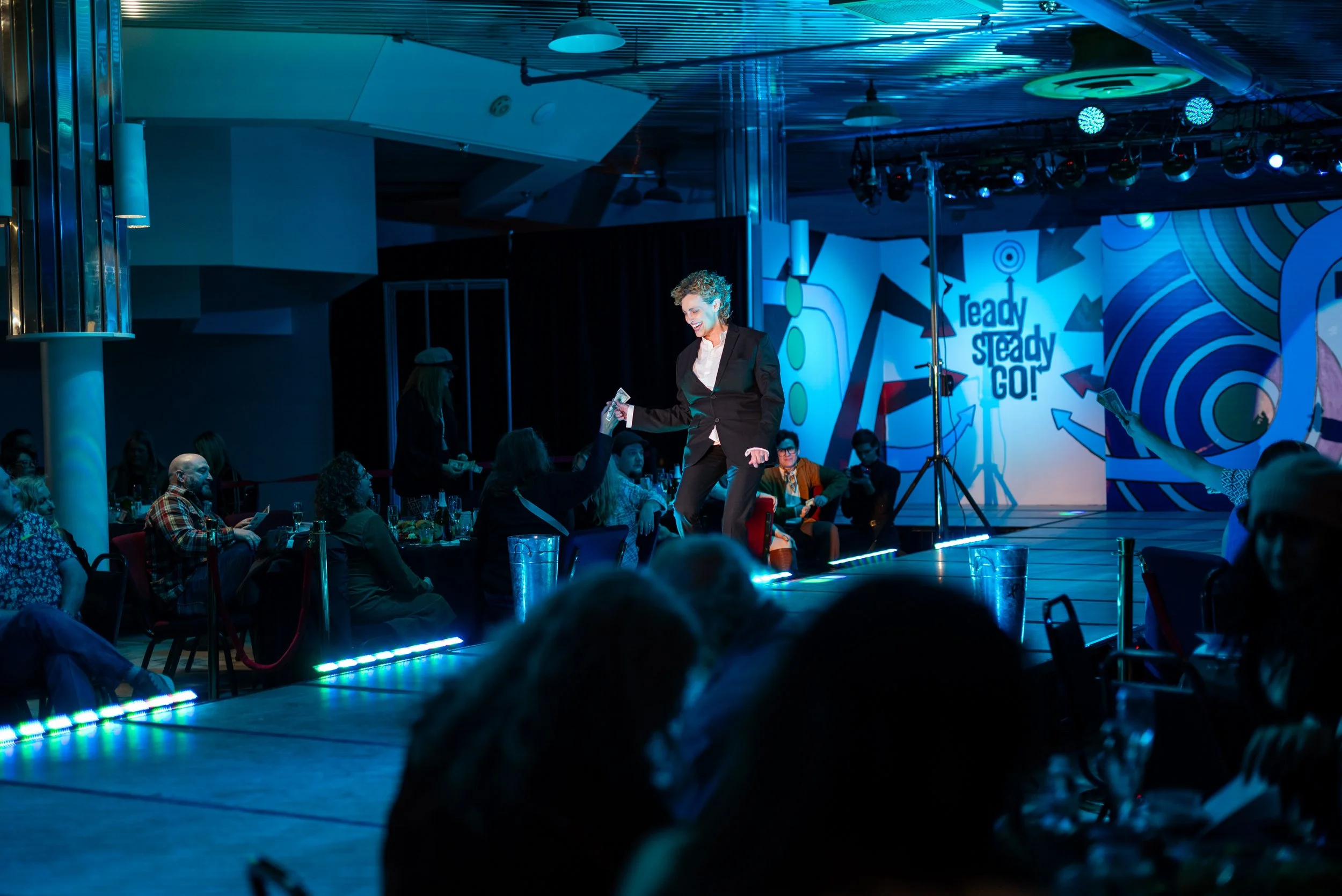 A woman on stage giving out money during an event with a sign that says 