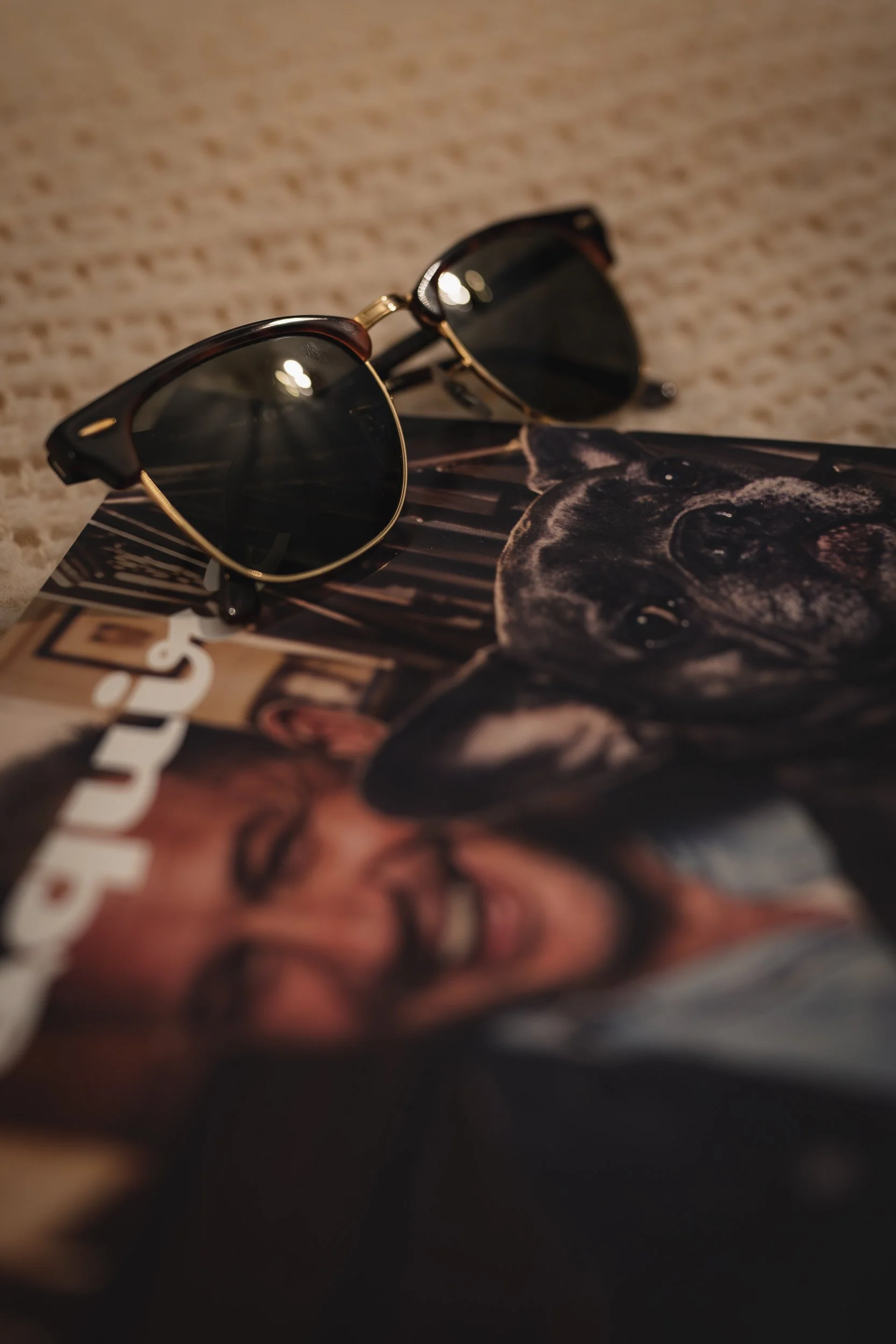 Sunglasses resting on a magazine that features a woman laughing and a German shepherd.