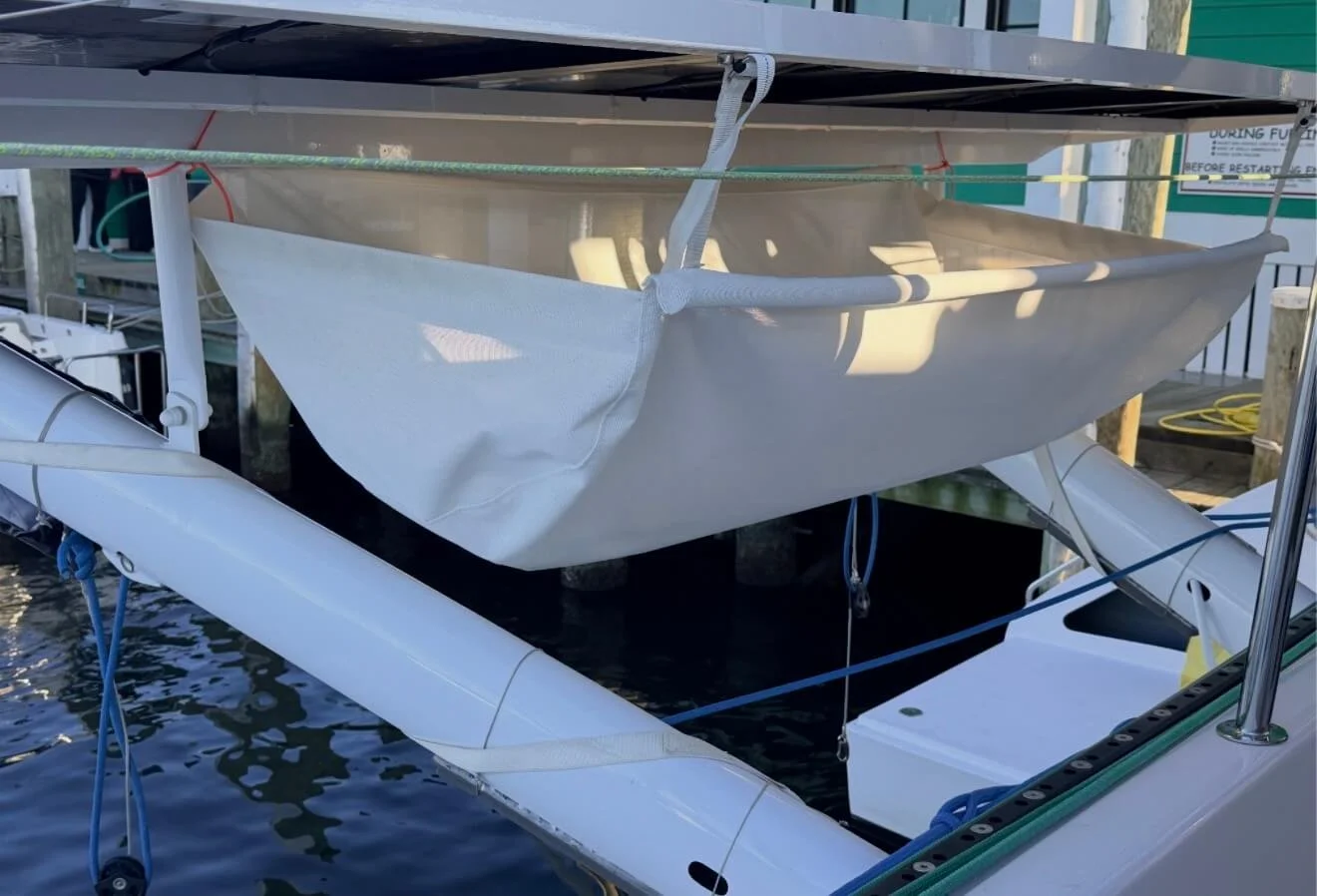 A white boat docked at a marina with a cover suspended over part of it.