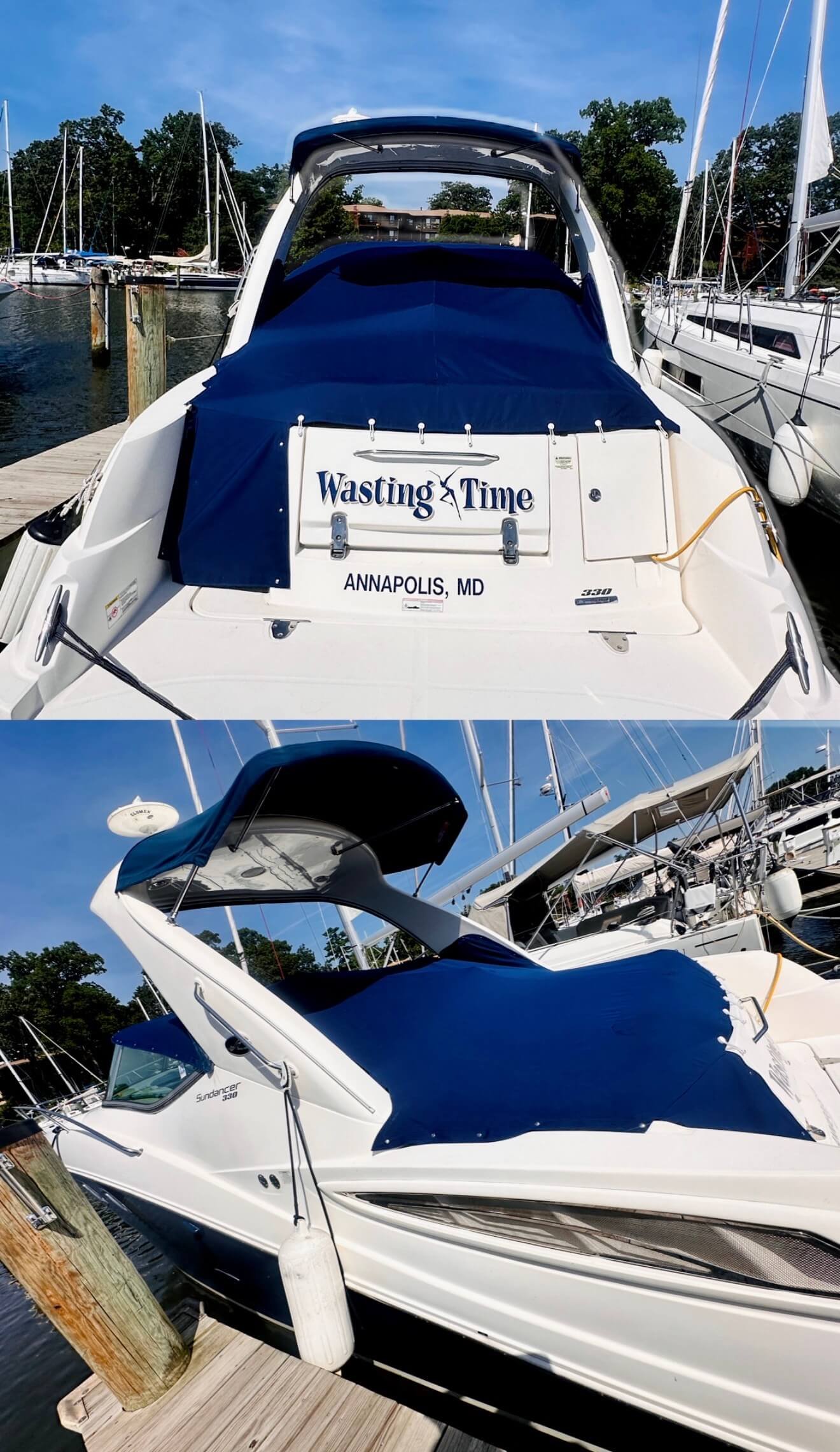 White motor yacht docked at a marina, with a blue cover over the cockpit. The boat has a sign on the back that reads 'Wasting Time,' and it’s registered in Annapolis, Maryland. The marina is filled with other boats, and there are trees and a clear bl