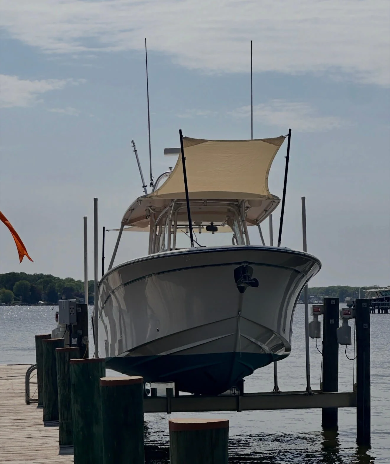 A boat docked at a marina with a wooden pier, under a partly cloudy sky.