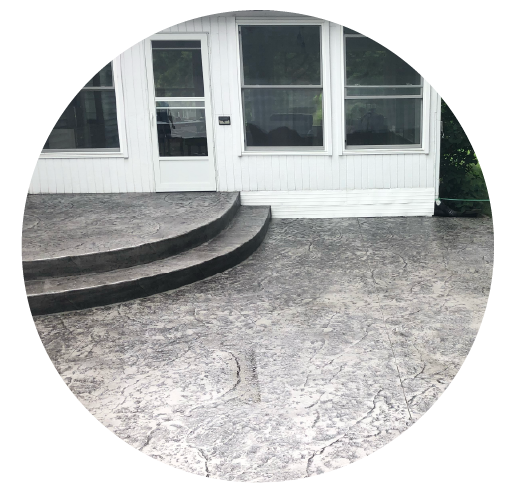 Back porch with three concrete steps leading to a patio, in front of a white house with large windows and a glass door.