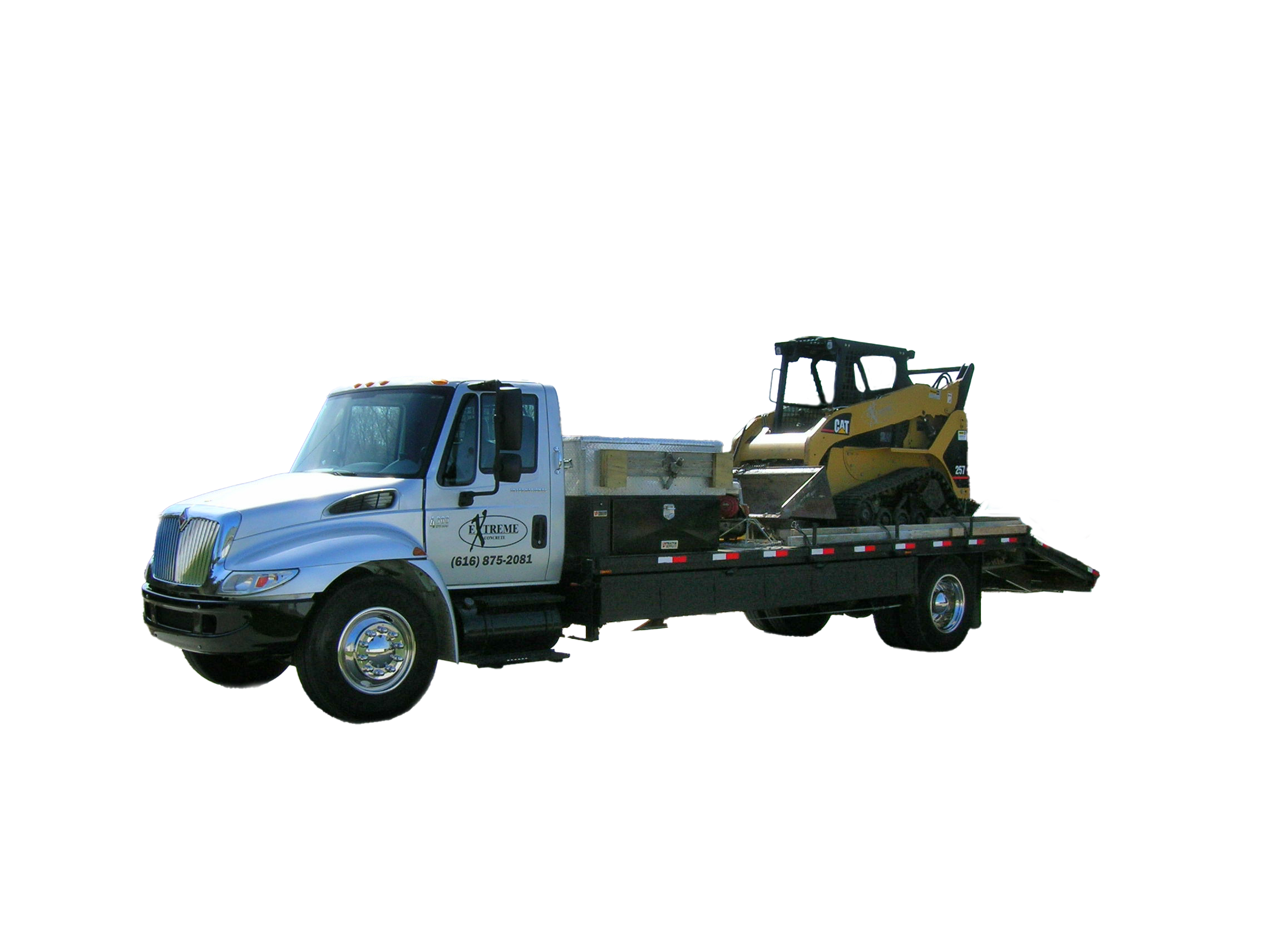White flatbed tow truck carrying a yellow CAT skid steer loader.