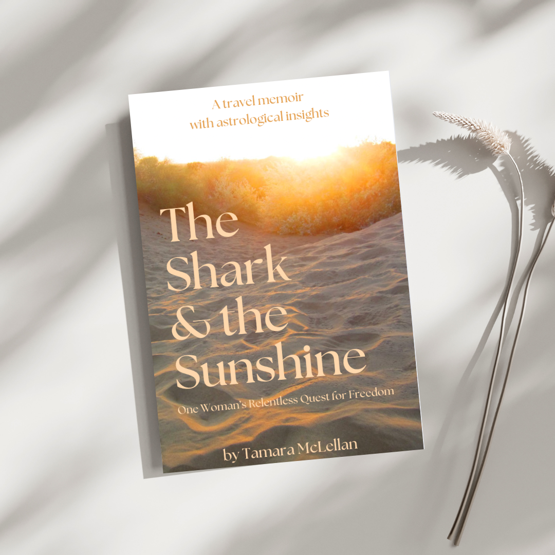 Book titled "The Shark & the Sunshine: One Woman's Relentless Quest for Freedom" by Tamara McLellan, featuring a cover image of a sandy beach with sunset lighting and a landscape of trees.