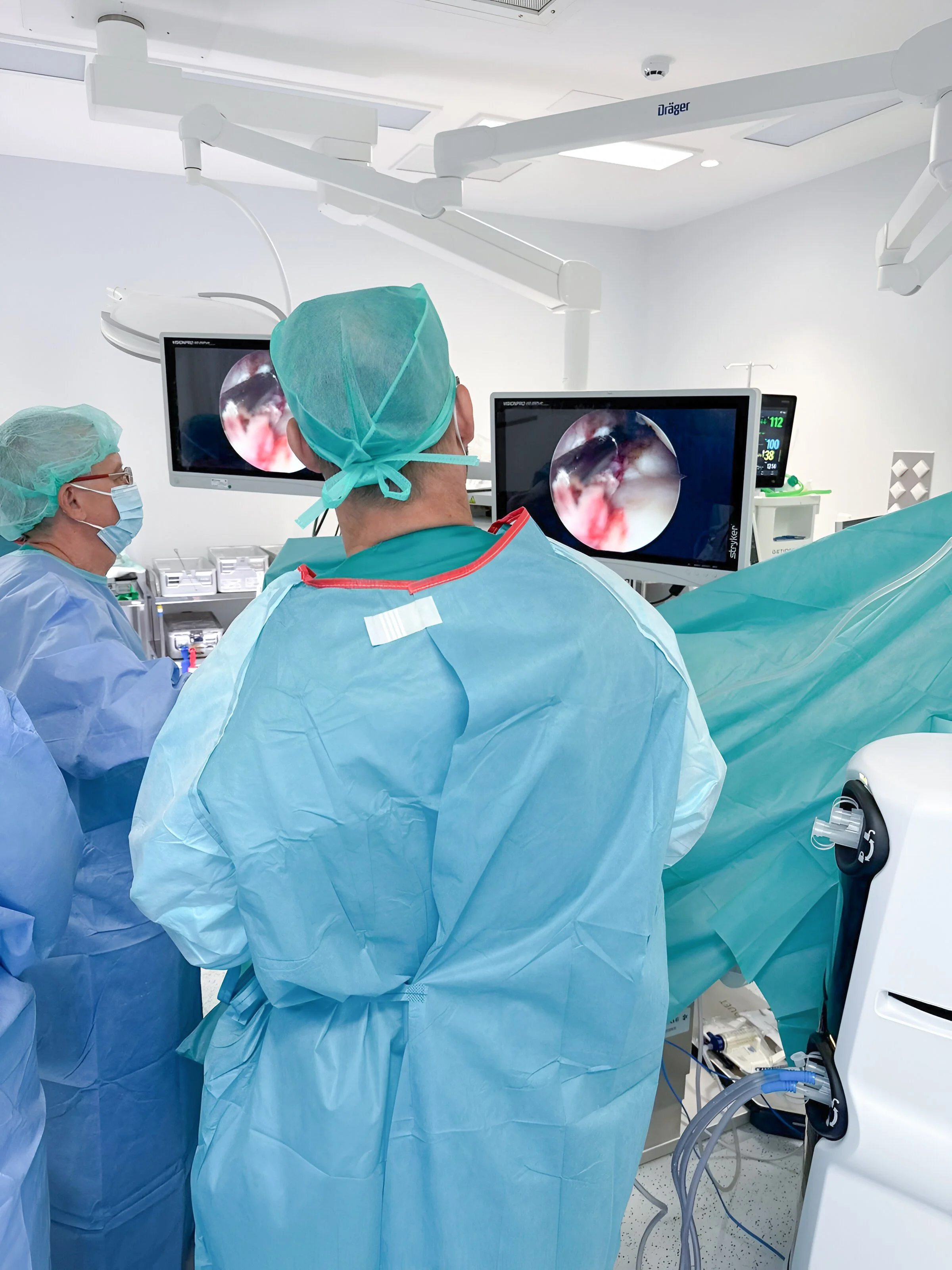 Doctor Gómez en sala de cirugía realizando un procedimiento con monitores digitales en el Hospital 12 de Octubre, en España.