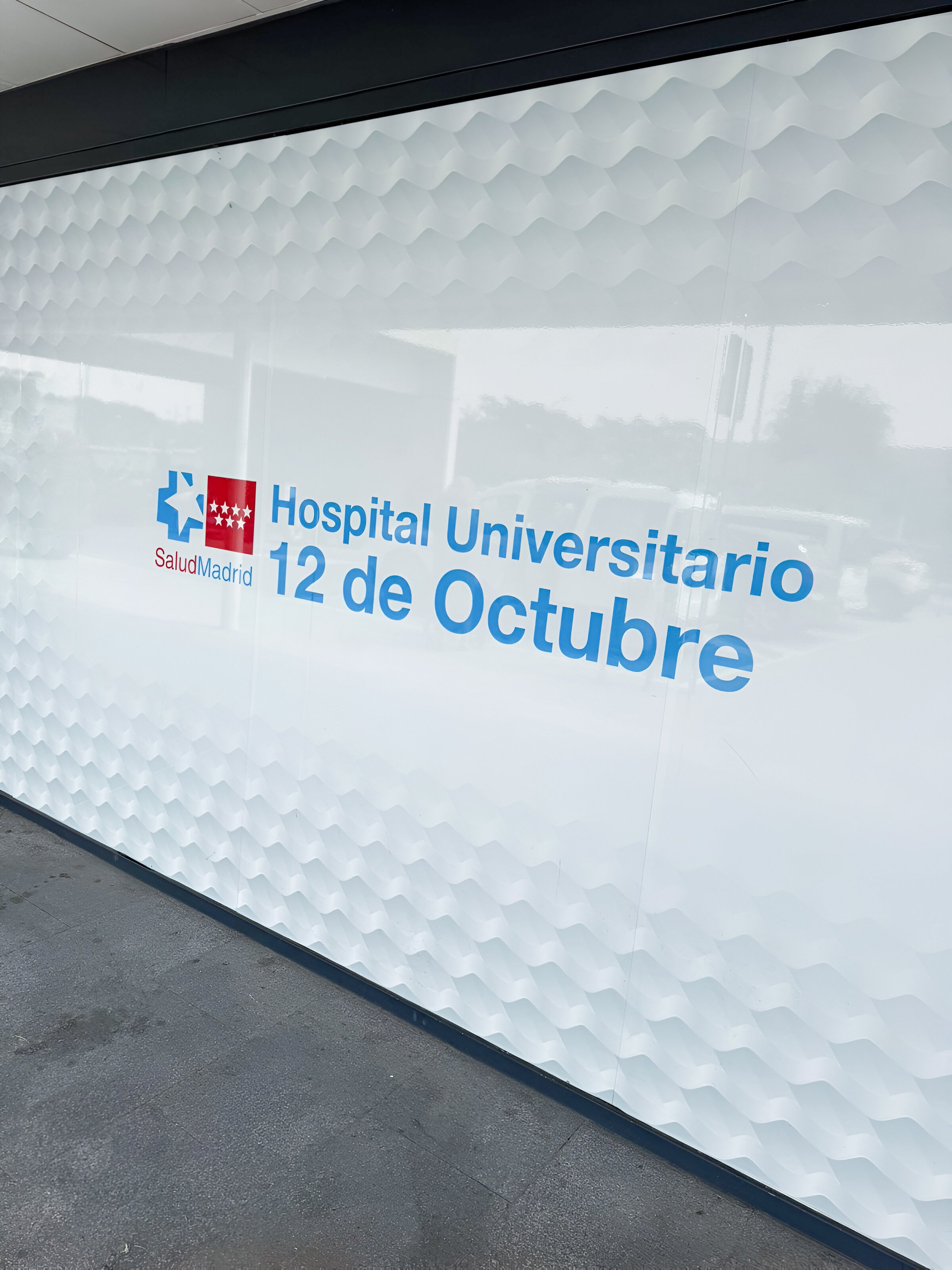 Fotografía de un costado del Hospital Universitario 12 de Octubre en España, con logotipo de Salud Madrid.