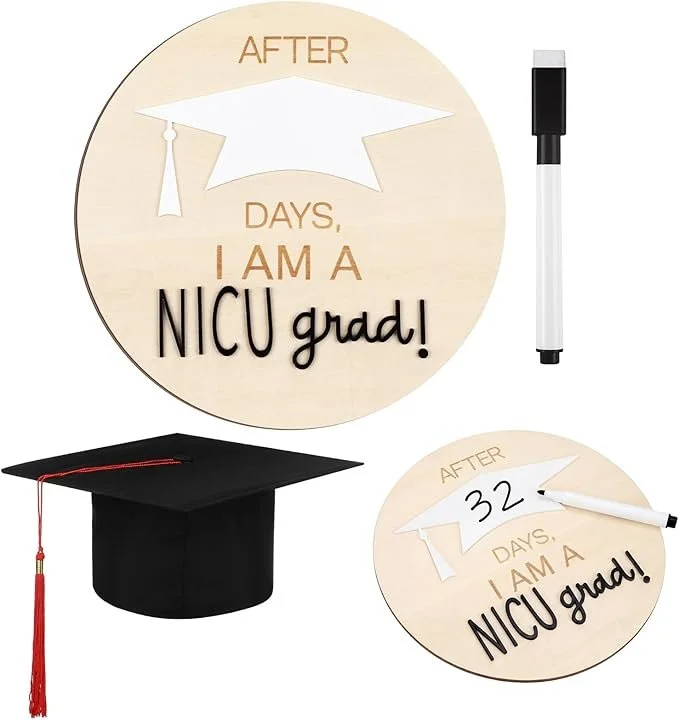 Round wooden sign with a graduation cap and the text "After ____ days, I am a NICU grad!" with a space to write the number of days, shown as 32. Also includes a black marker for writing and a black graduation cap with a red tassel.