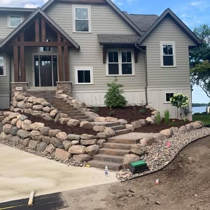 House with stone stairs and landscaping in progress.
