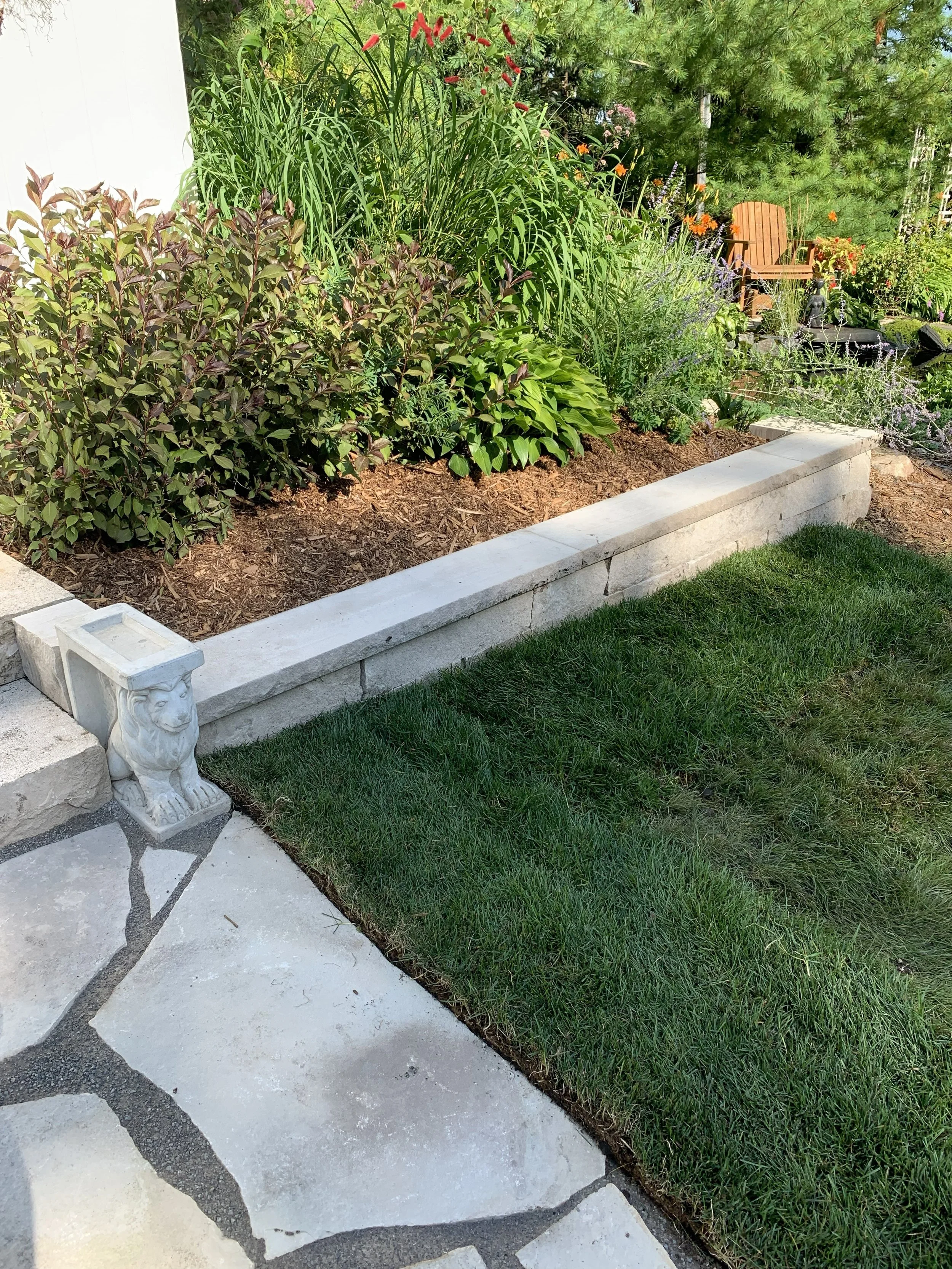 Lawn with colorful Adirondack chairs around a fire pit, trees, boat dock, and boats on a lake in the background.