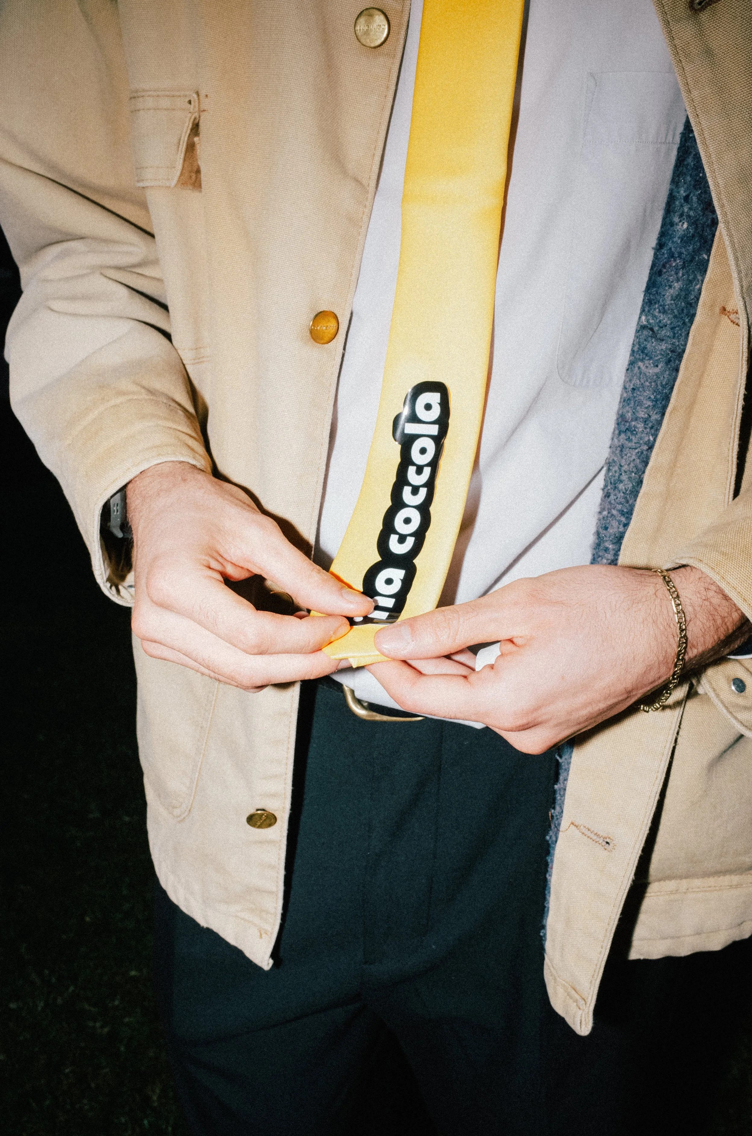 Person in beige jacket holding a yellow strap with a black and white 'la coccola' logo.