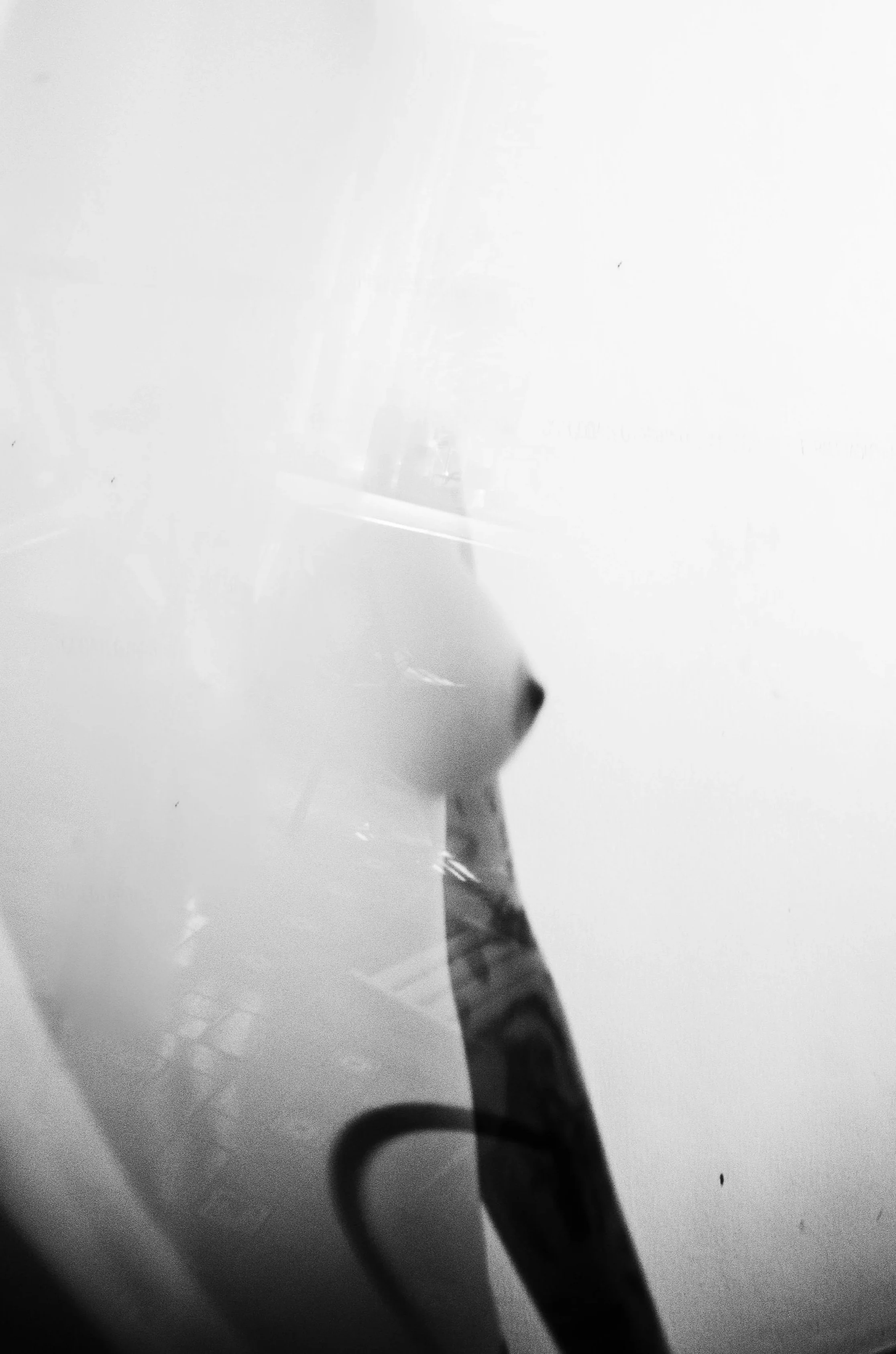 Close-up black and white photo of a paintbrush with bristles pointing upward and a handle with a pattern, against a white background.