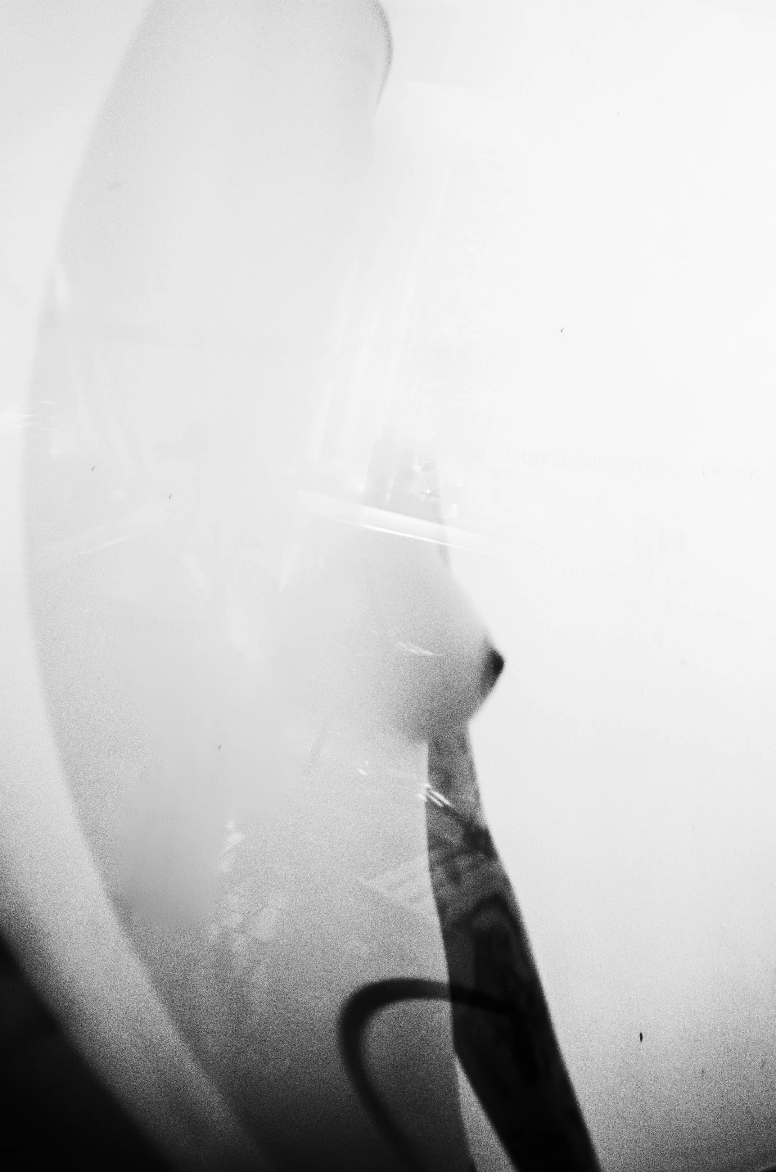 Close-up of a person's face reflected in a mirror or glass, with a dark background.